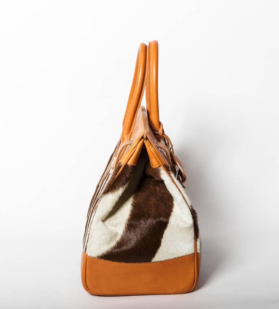 Ralph Lauren Zebra Print Calf Hair Ricky Bag 33 with Tan Leather.
 Bag features rolled top handles, folded flap top with slide-lock clasp and belted straps, and one zip and open pocket. 4 inch strap drop.
Comes with original duster.