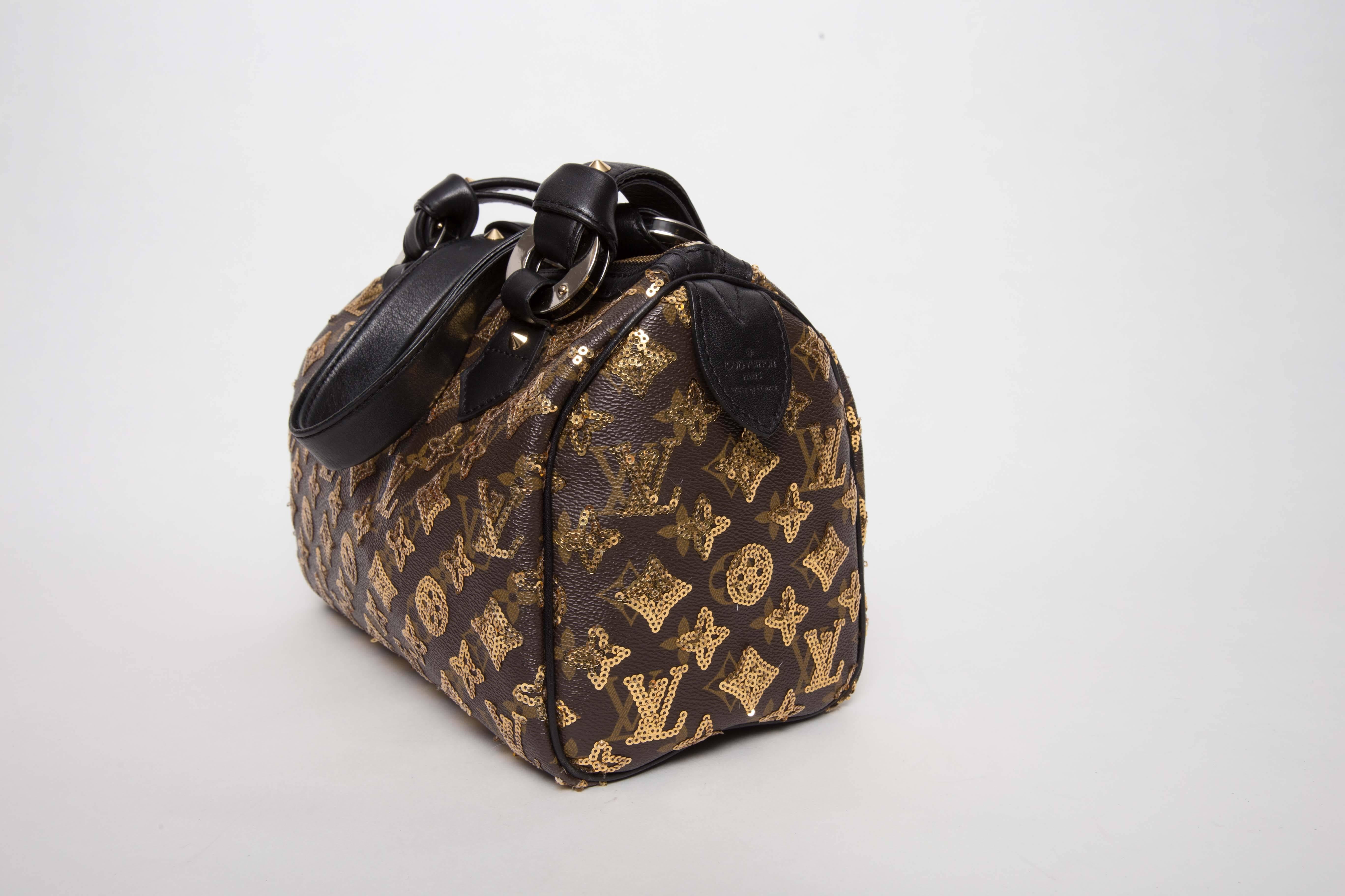 Louis Vuitton Monogram Eclipse Speedy 28 features the traditional monogram toile canvas, with sewn gold sequins. The bag has strap leather handles with large brass handle loops. There is a pad of leather for the base and base feet. The interior is a