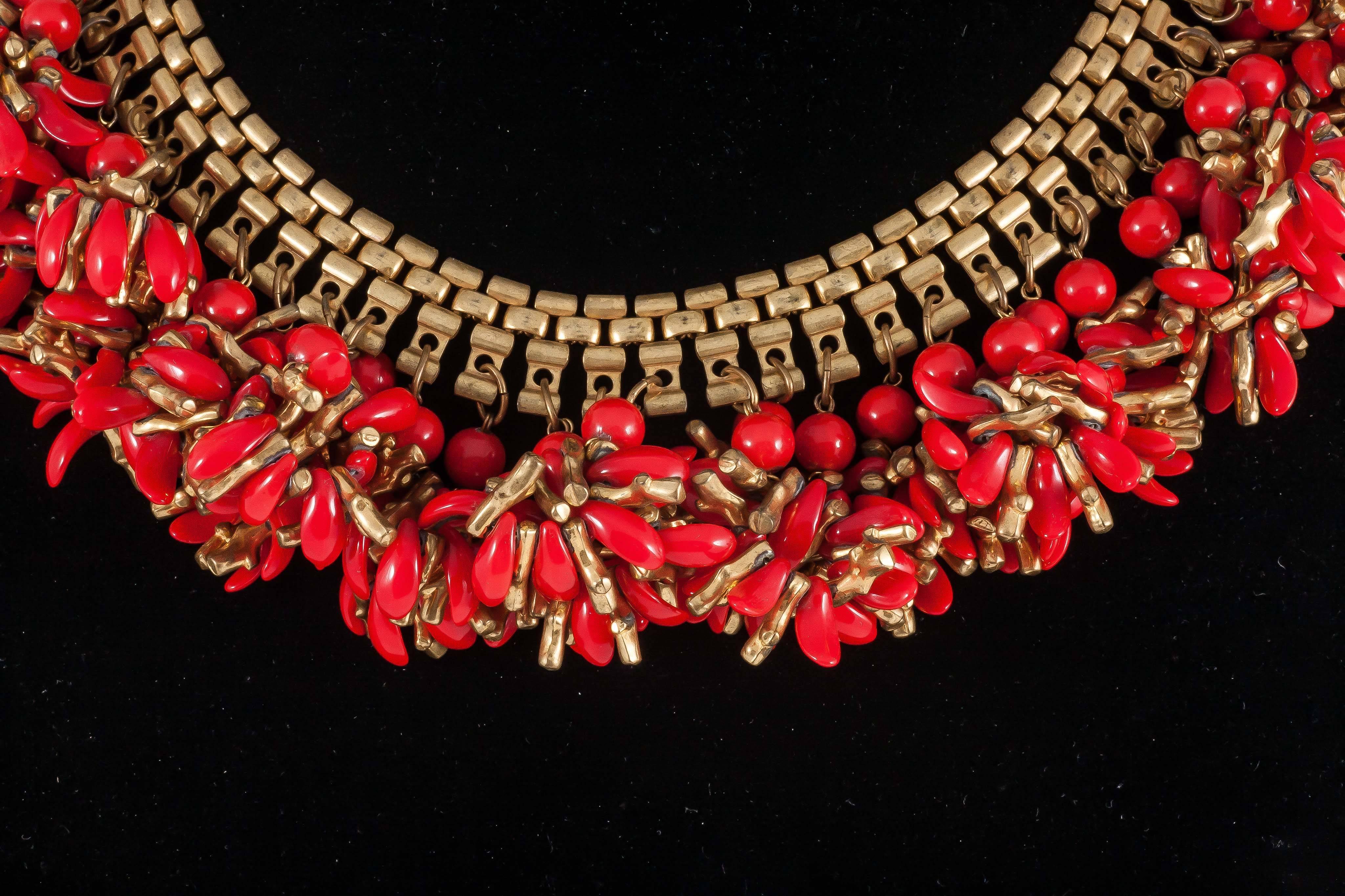 A joyful Miriam Haskell necklace, in a vivid coral red, and gold, the red petals are made from plastic, as are the small 'gold branches of coral' . Many individual clusters of gilt coral and red leaves are suspended from a flat gilt brick pattern