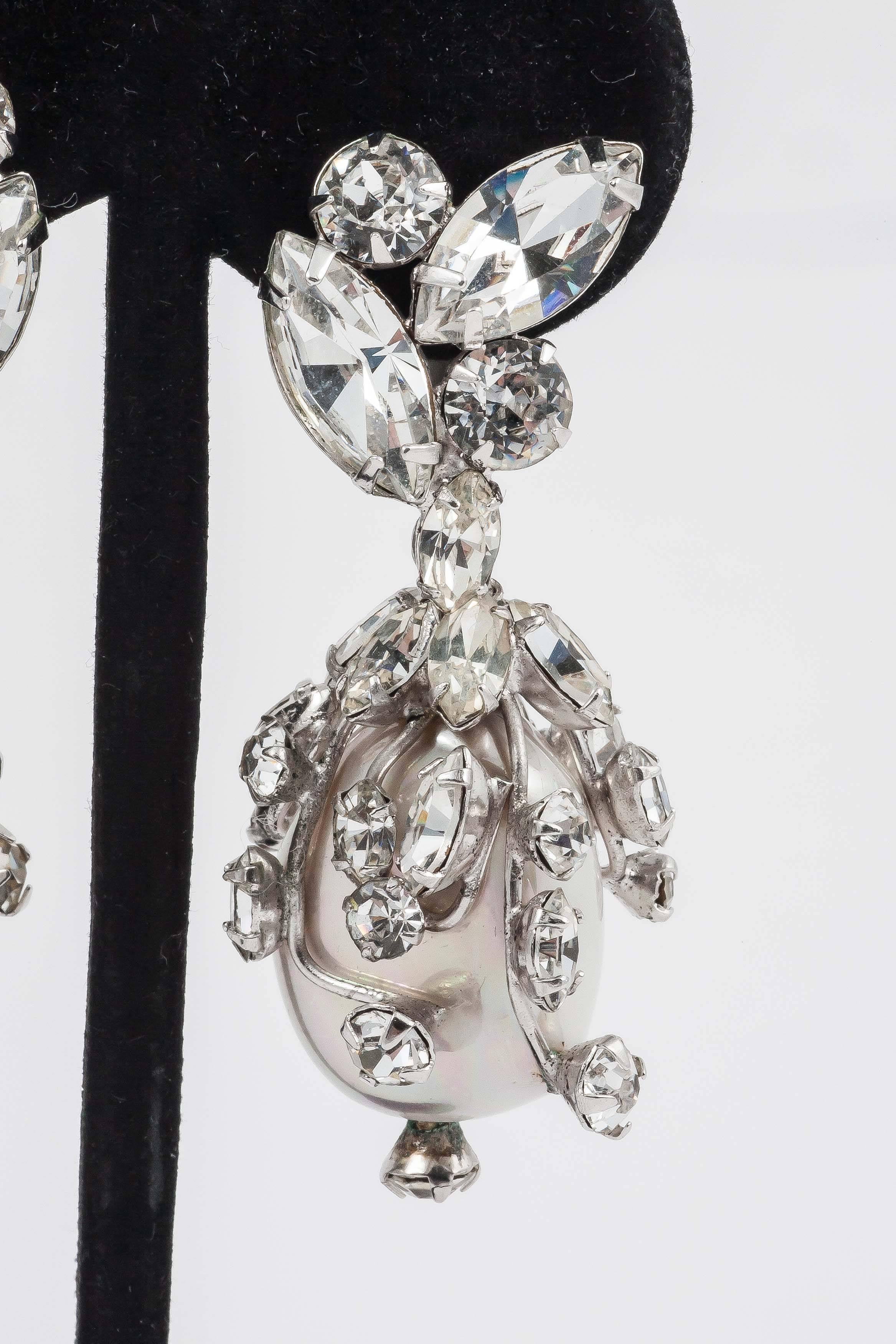 Highly sculptural Schreiner earrings perfect for a formal wedding or red carpet event. Schreiner has taken a faux mabe pearl and enrobed it in rhodium plated tendrils all ending in different shapes of clear paste, even the end piece has a paste