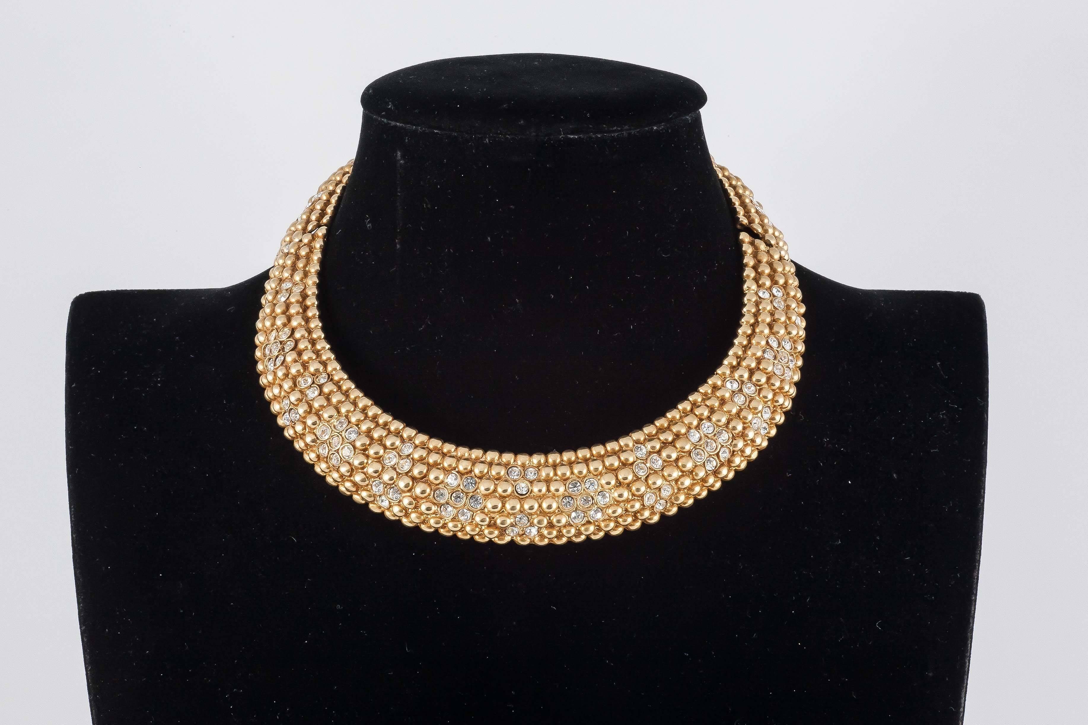 Gilt bobbles with paste floral highlights make up this gently curving rigid collar. Beautifully made this is a  smart classic 1980s standard from YSL. 
Yves Saint Laurent was born in 1936, and became one of the 20th Century’s most famous and