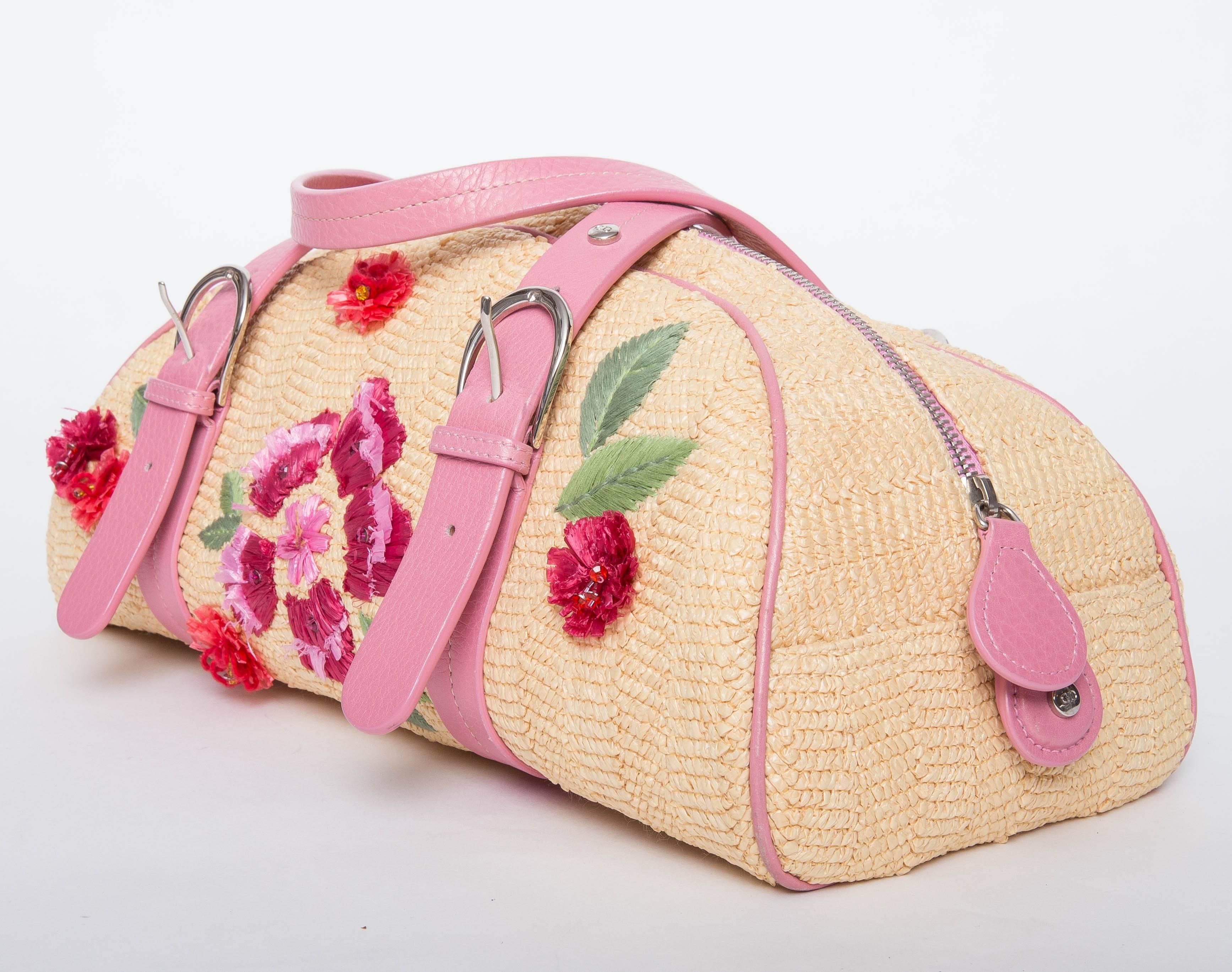 Dior Wicker Frame Bag with Raffia Flowers features soft grained pink leather trim, colorful raffia flowers on the front, silver metal hardware, and pink leather handles.The logo textile lined interior has a zipper pocket with a leather zipper tag
