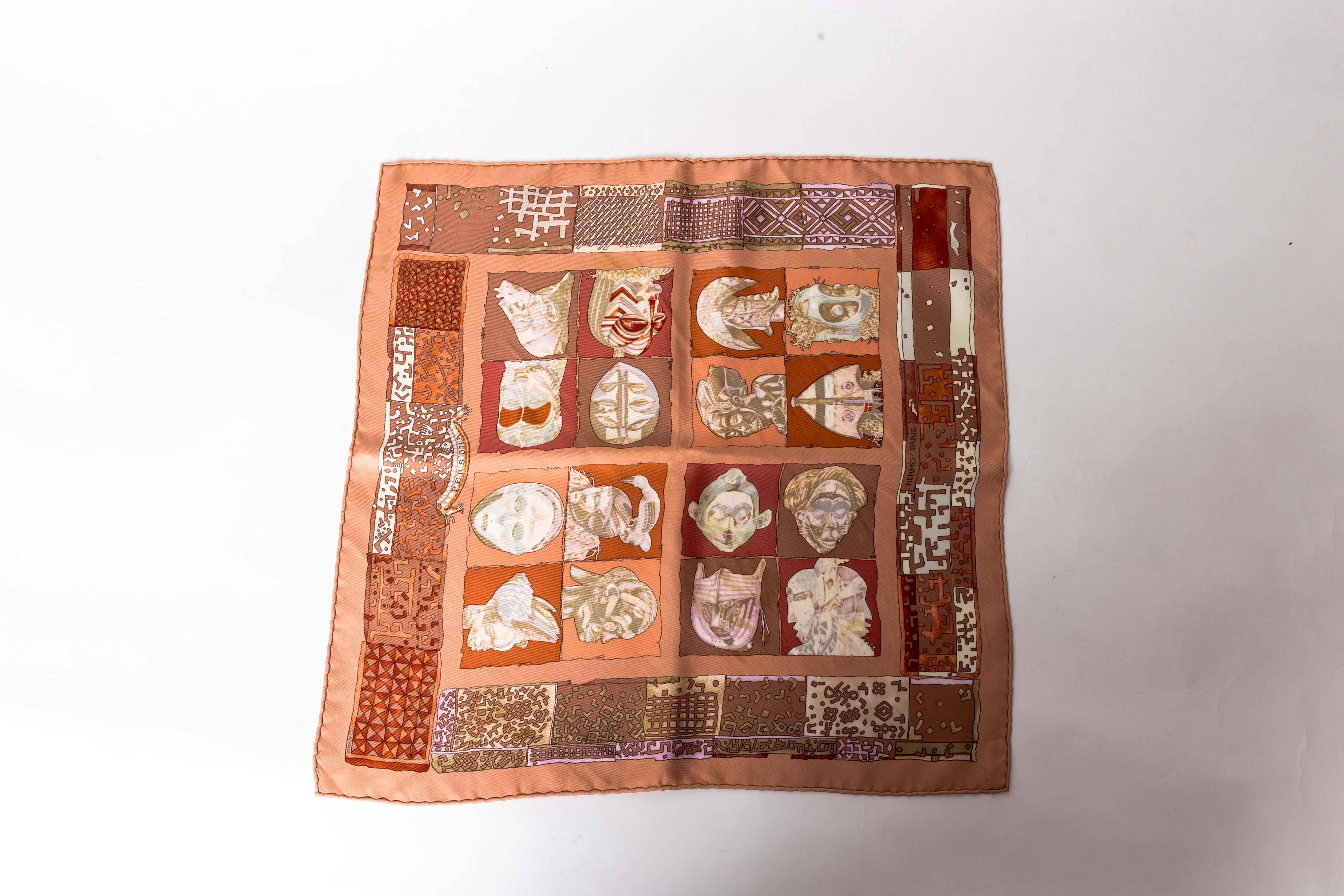 Lovely Hermes Pocket Square in Shdes of nude and terracotta.
Titled Persona this silk pocket square is stamped Hermes Paris and features sixteen heads within a border of geometric patterns. 
Lois Dubigeon is the artist behind this silk scarf and her