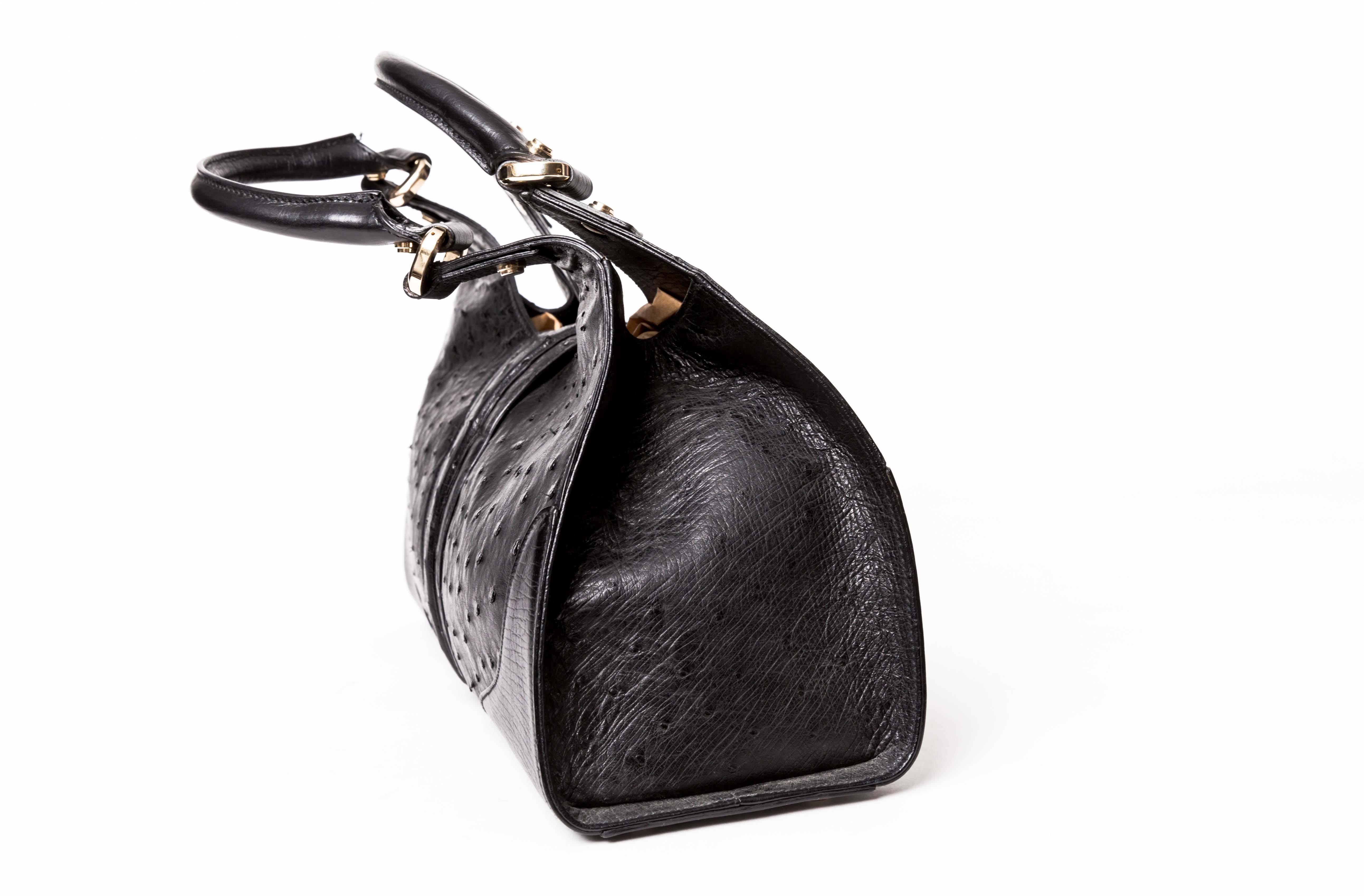 Gucci Black Ostrich Sherry Bag with Gold-Tone Hardware features pale gold hardware, two top handles, five protective metal feet, 