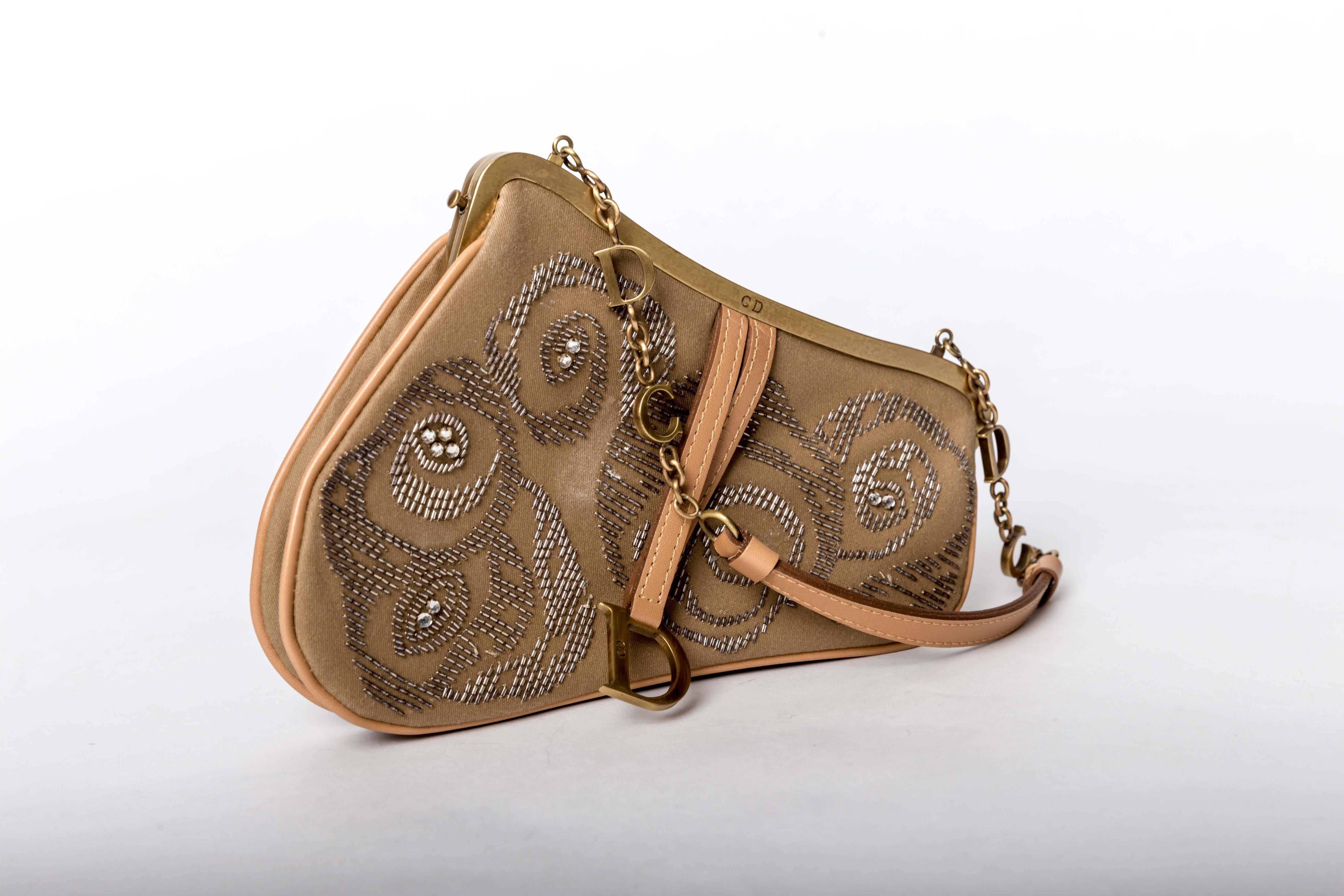 Christian Dior Limited Edition Mini Beaded Saddle Bag with Gold Logo Hardware features tan fabric with natural leather trim, patterned beading and crystals, one interior flat pocket encasing a leather trimmed mirror.
Handle drop 5 inches.
Stamped