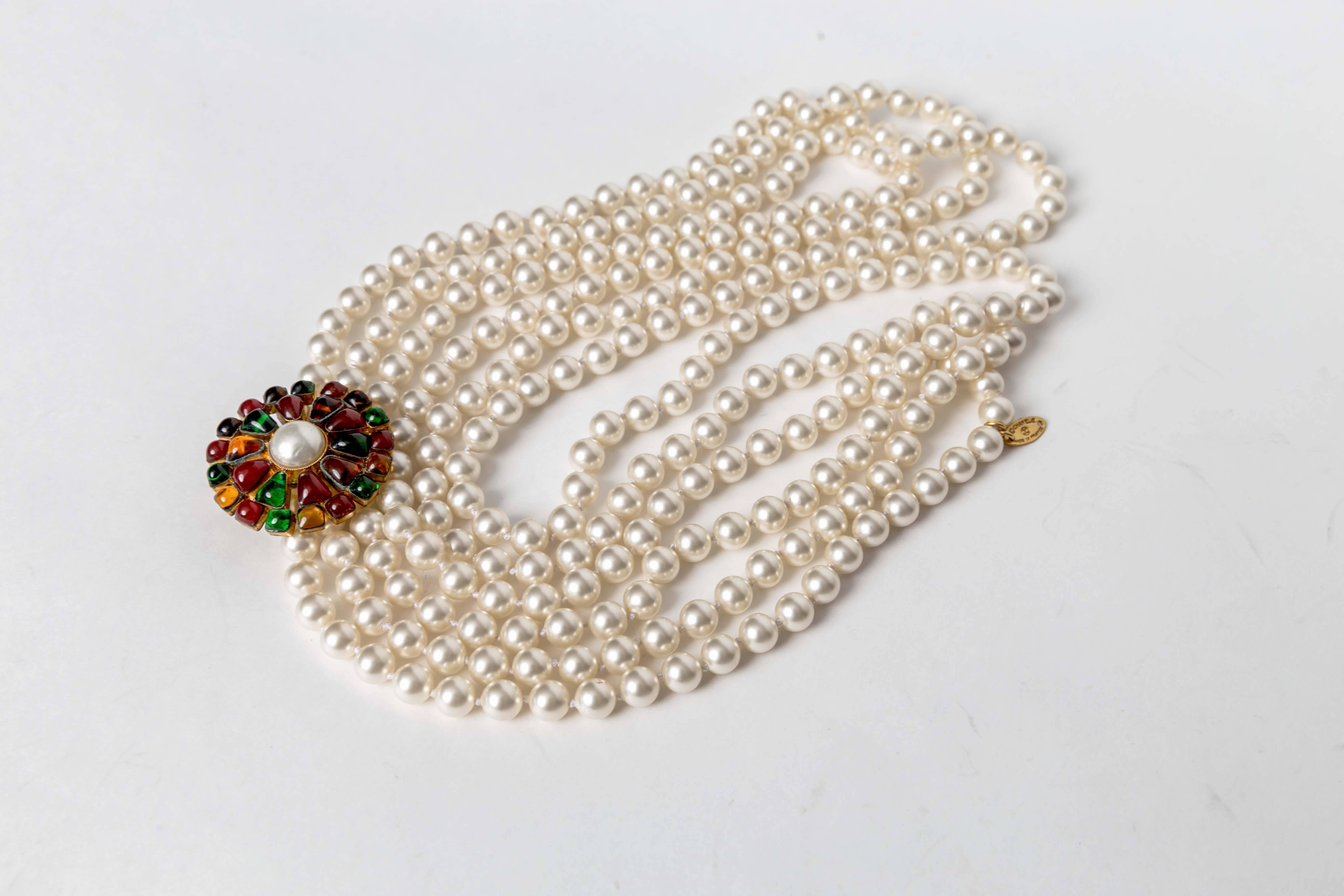 Chanel Multi-strand Pearl & Pâte de Verre Brooch Necklace features three graduated Chanel faux pearl strands, purple and a red,green,and amber pate de verre brooch encircling a larger pearl. 
Stamped 