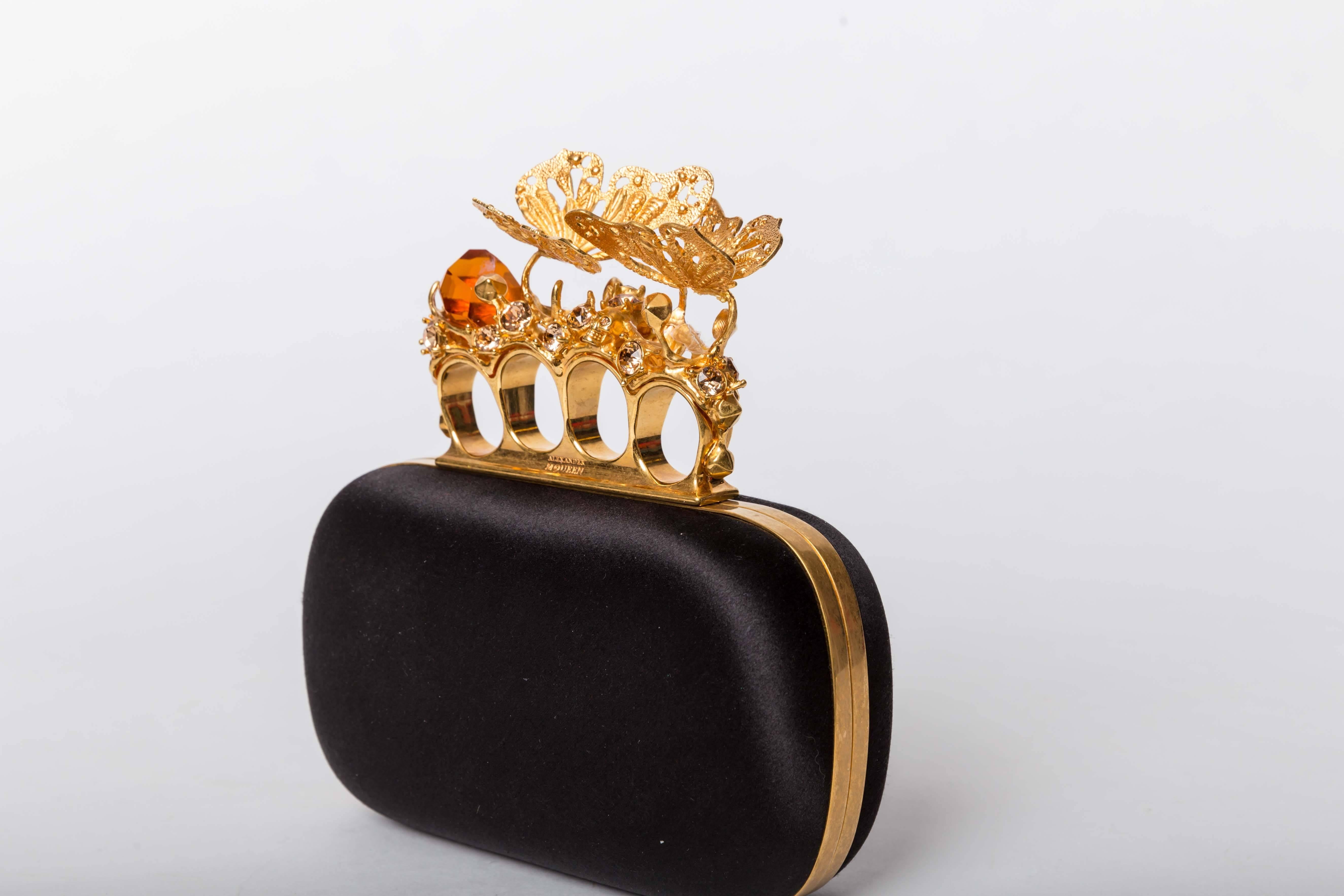 Alexander McQueen Butterfly Knuckle-Duster Box Clutch Bag features golden butterflies perched on large amber colored crystal stones. Trimmed with gilded brass hardware and fitted with iconic Swarovski-studded mini skulls, golden-framed, hard-shell