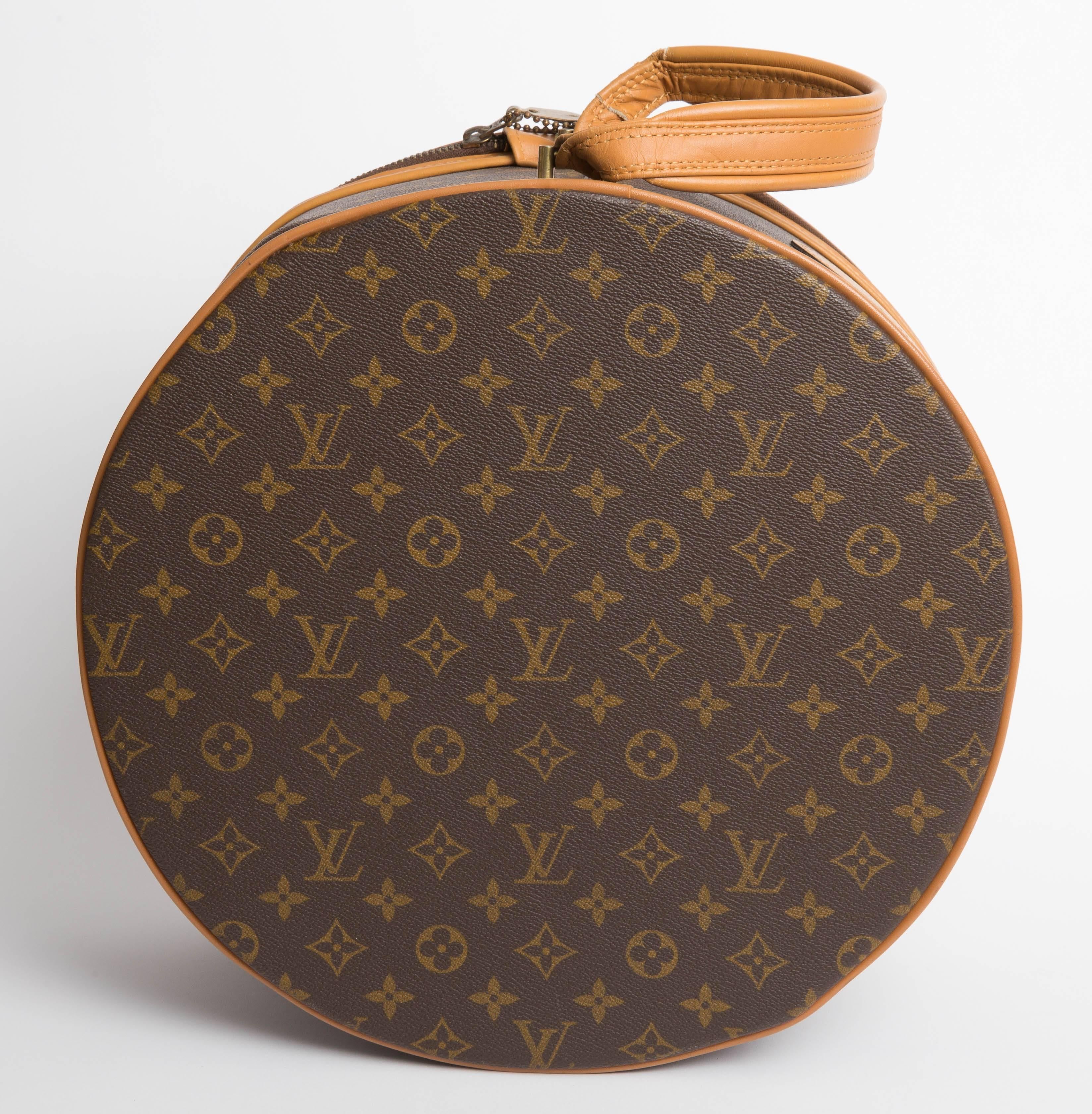 Louis Vuitton Vintage Monogram Boite Chapeaux Hat Box features  a rounded case with flattened bottom, vachetta handle and trim, and lock and key. The inside is done in a textile with an elastic pocket inside. Made exclusively for Saks Fifth