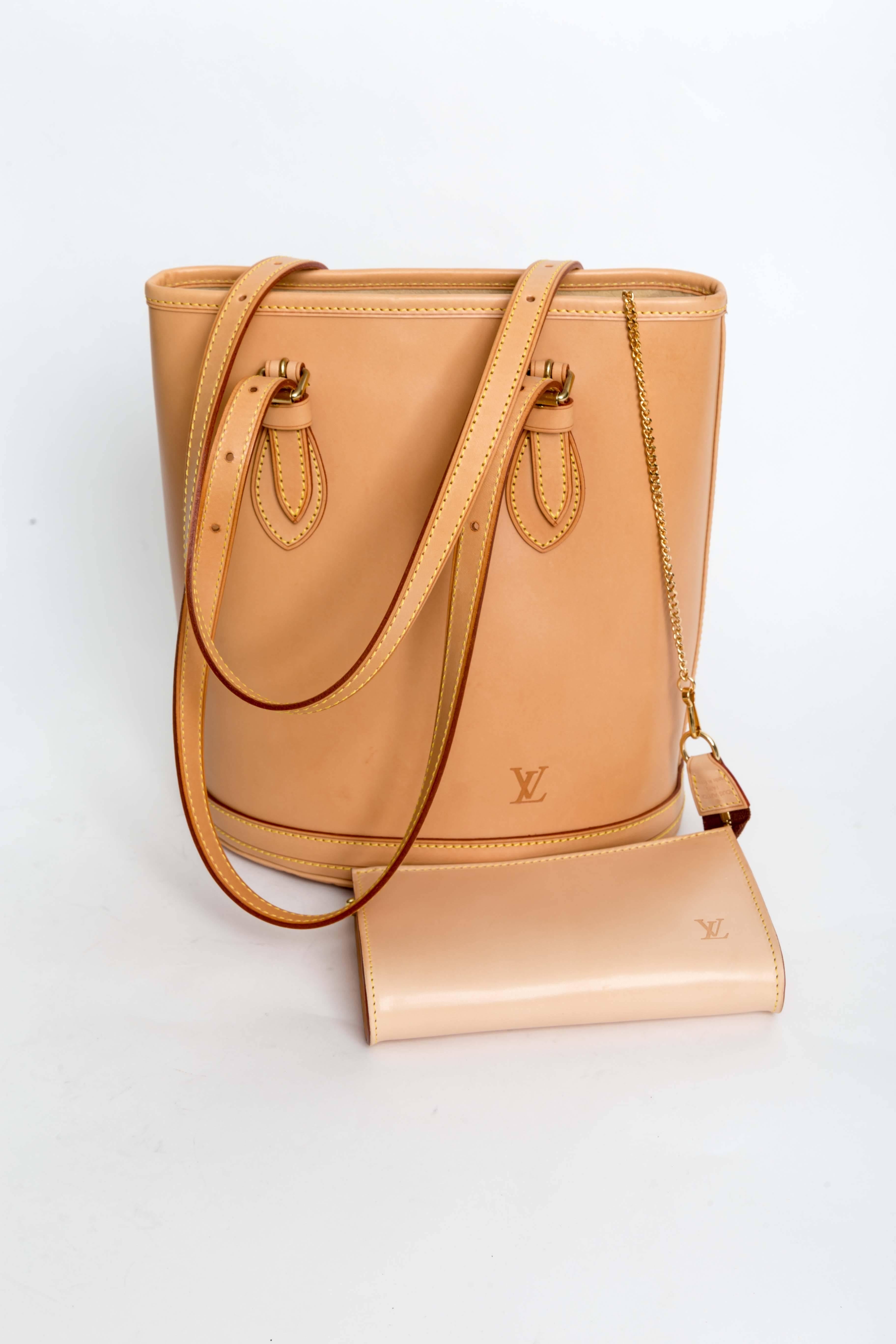  Louis Vuitton Petit Bucket Bag in Tan Vachetta Leather features  brass hardware, dual adjustable shoulder straps, yellow contrast stitching throughout, embossed logo embellishment at front, beige Alcantara interior, dual pockets at interior walls;