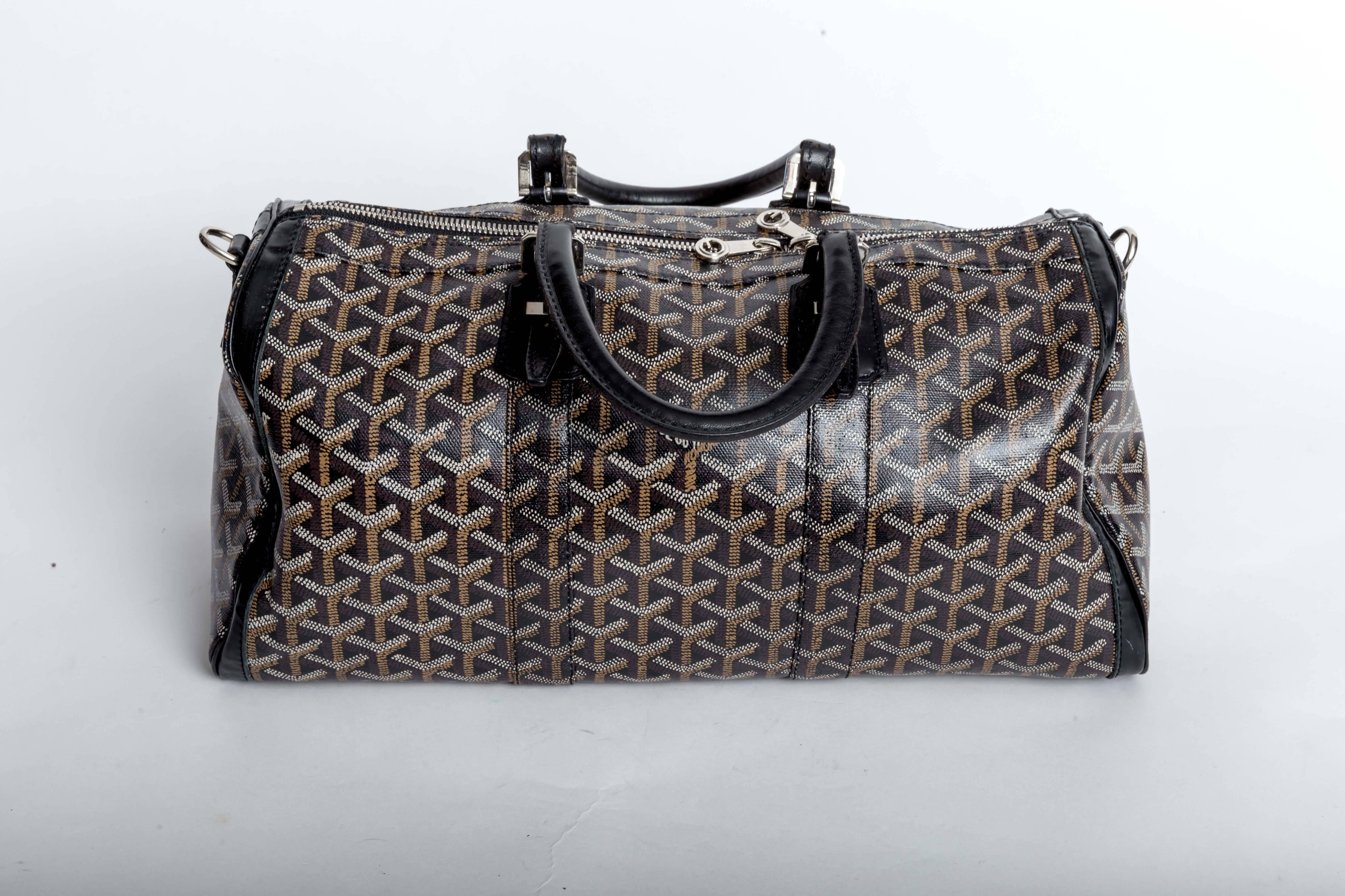 Goyard Croisiere Medium 35 Boston Bag Canvas/Leather Black  features a top zip closure, rolled leather handles with adjustable buckle closures and is trimmed in matching leather. The canvas interior has one zip pocket. Removeable shoulder strap