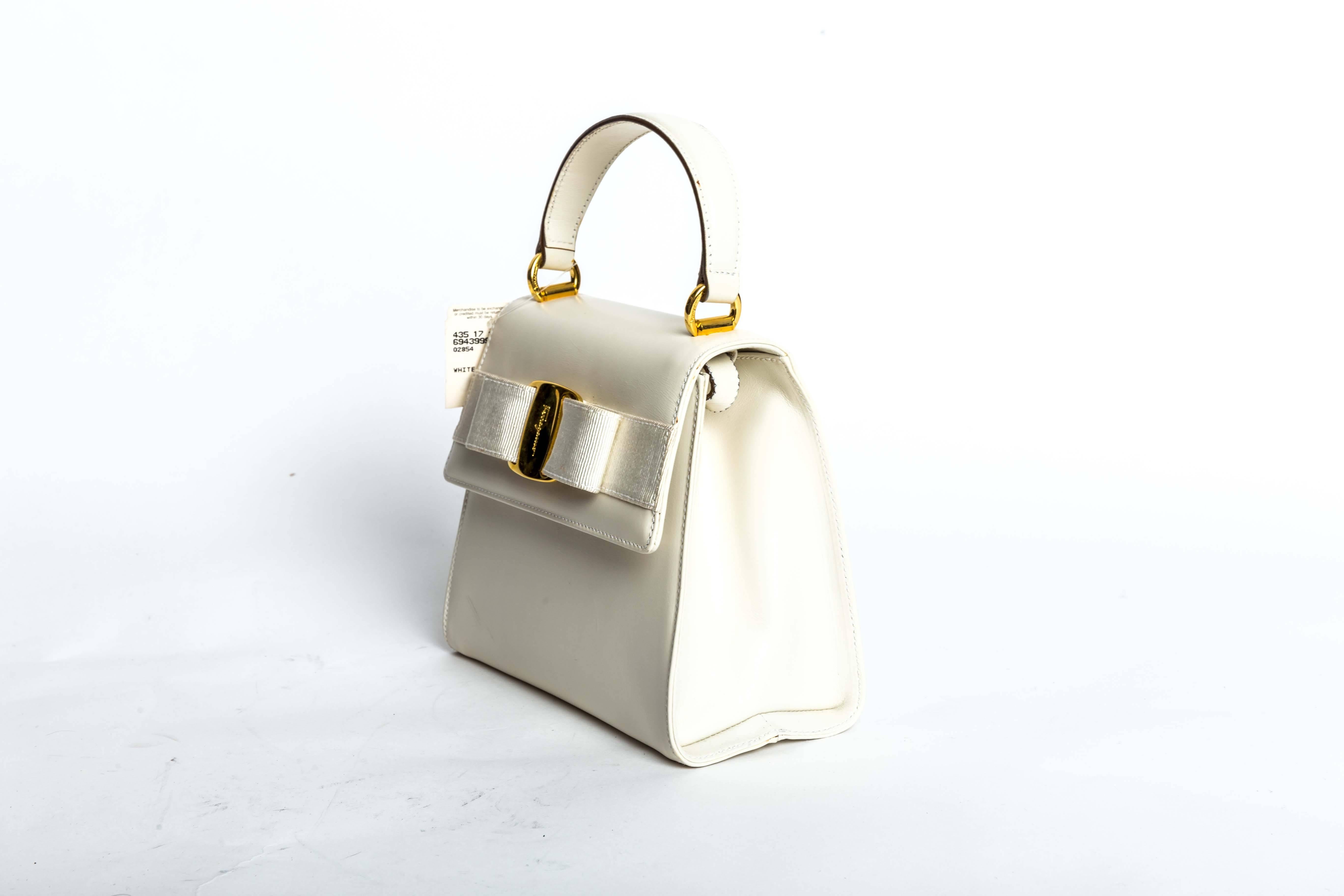 Ferragamo Vintage Vara Bow Two Way Bag in White Leather features gold hardware, grossgrain bow, magnetic closure, interior zip pockets, and removeable leather strap.
Strap drop 3.5