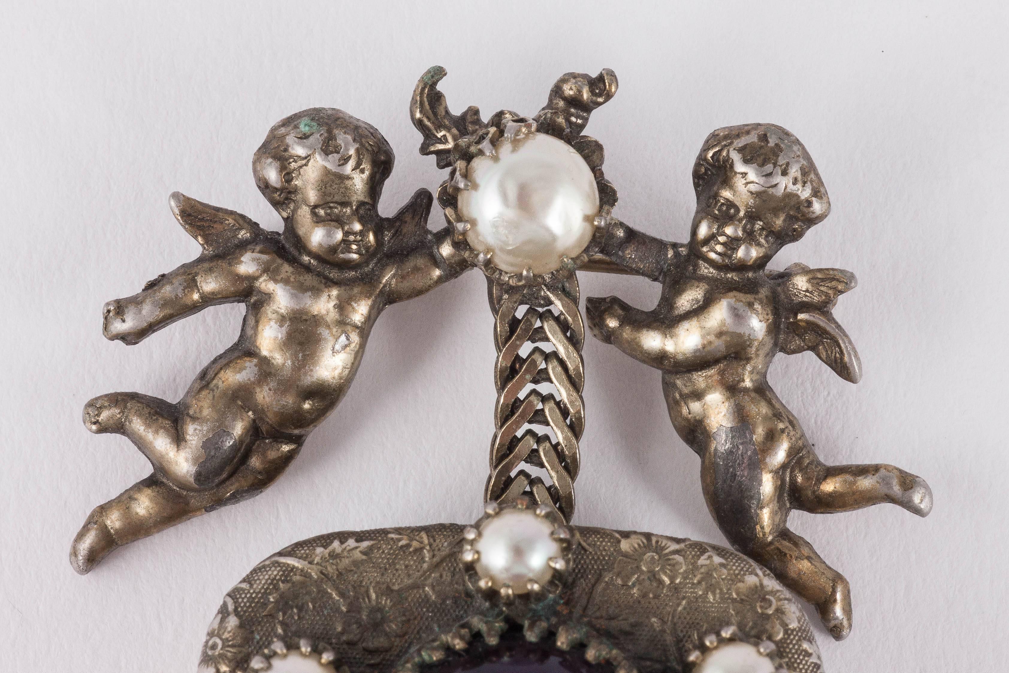 Very rare, highly unusual and very collectable Christian Dior (by Mitchel Maer) drop brooch, a 'musical box  (that plays La Vie En Rose), carried by two cherubs or 'putti', with a pearl place in between them, all in a patinated silvered metal. The