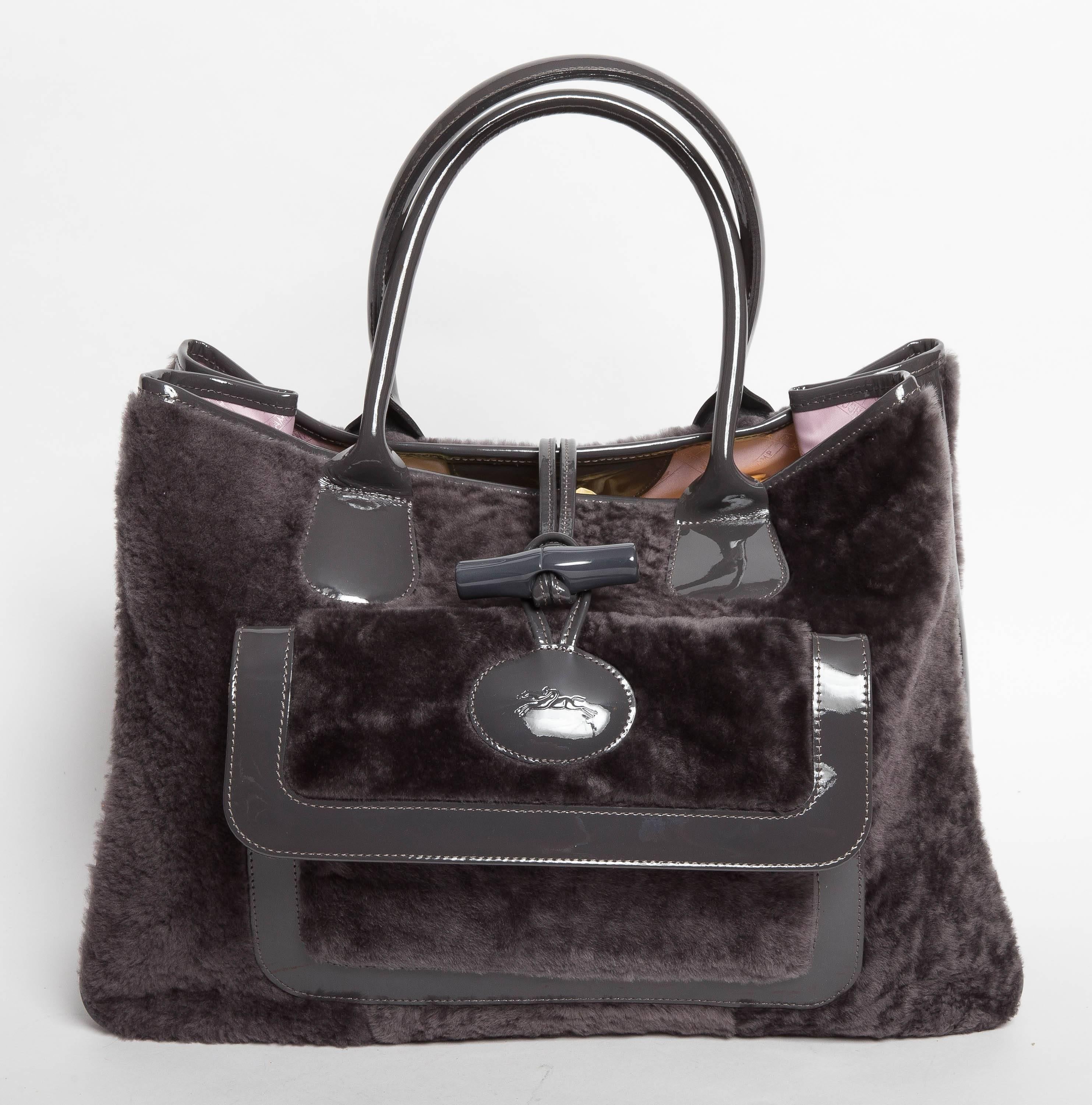 Beautiful shearling tote in grey with  patent trim and toggle closure. This tote is in excellent condition and features a large front exterior pocket as well as a large inner zip pocket. Nylon pink Longchamps lining is in immaculate condition and