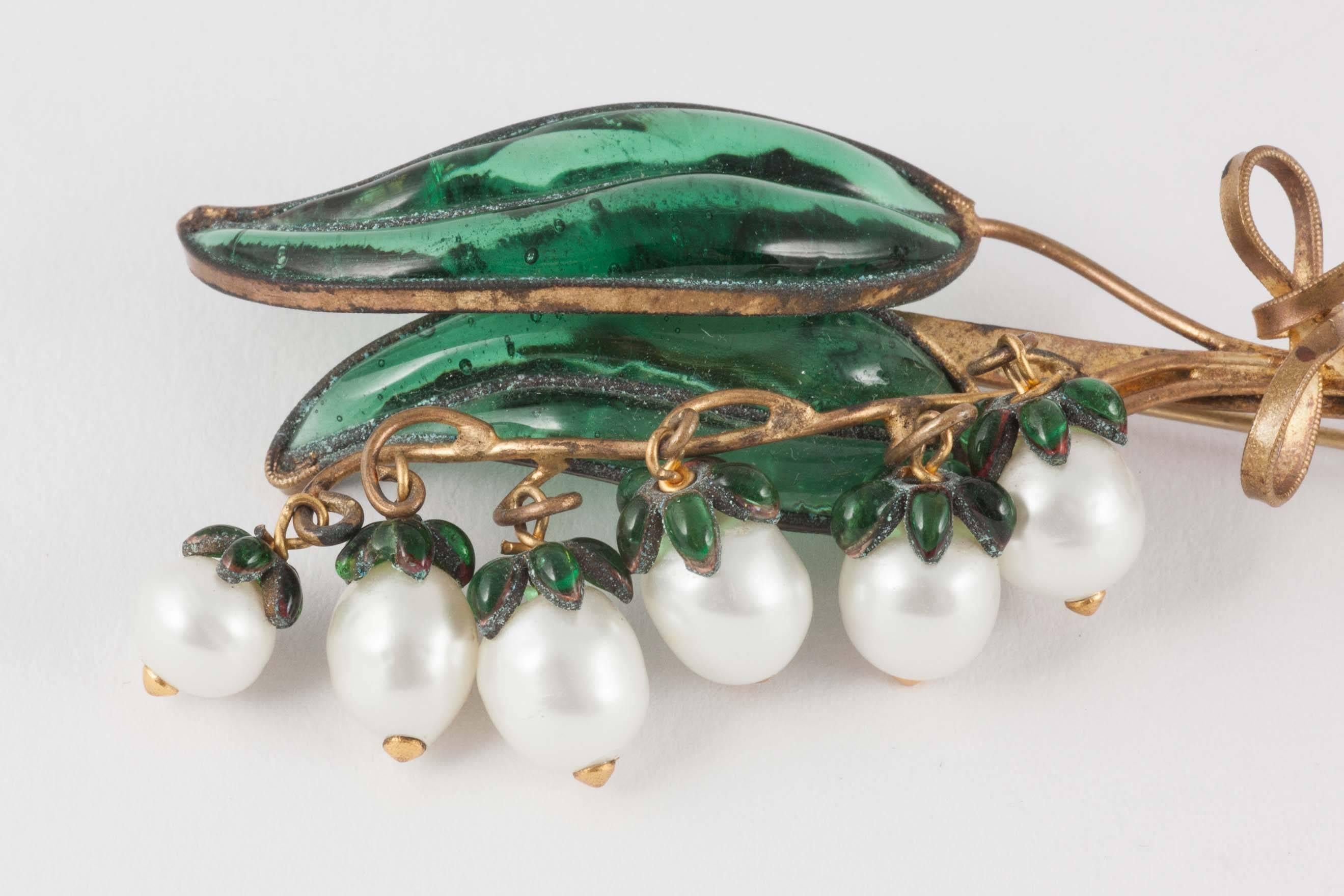 One of the most iconic images of the House of Dior, this delicate and highly feminine 'Lily of the Valley' or 'Muguet' brooch is the work of the artisan workshop Maison Gripoix, made of poured glass, nacred pearls and gilt metal. 'Lily of the