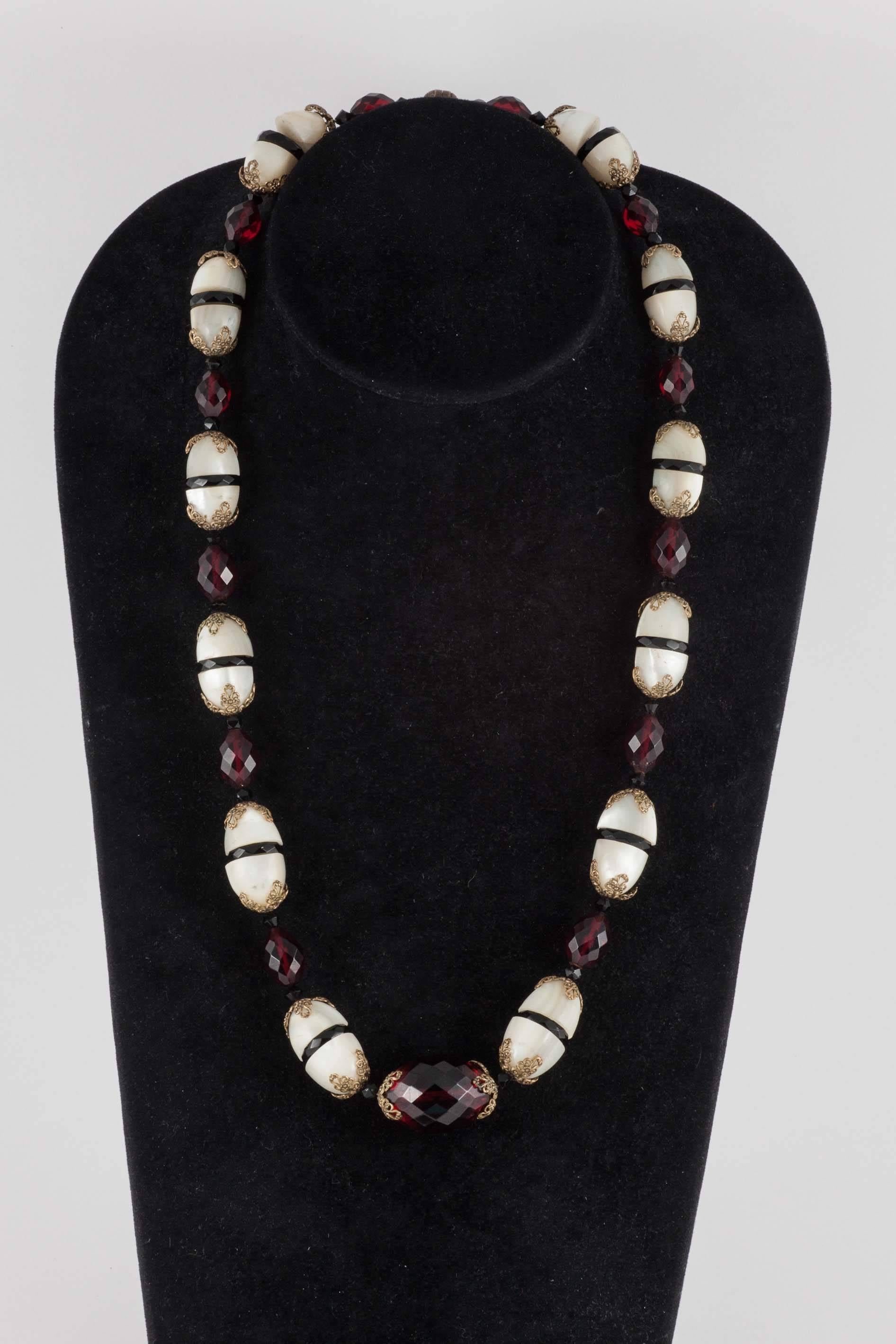 Beautiful and very unusual, maker unknown, these two beaded necklaces are a variation of each other. One, larger,  in ruby/garnet and black coloured glass and large pieces of carved mother of pearl, with gilt metal caps/decoration, the other,
