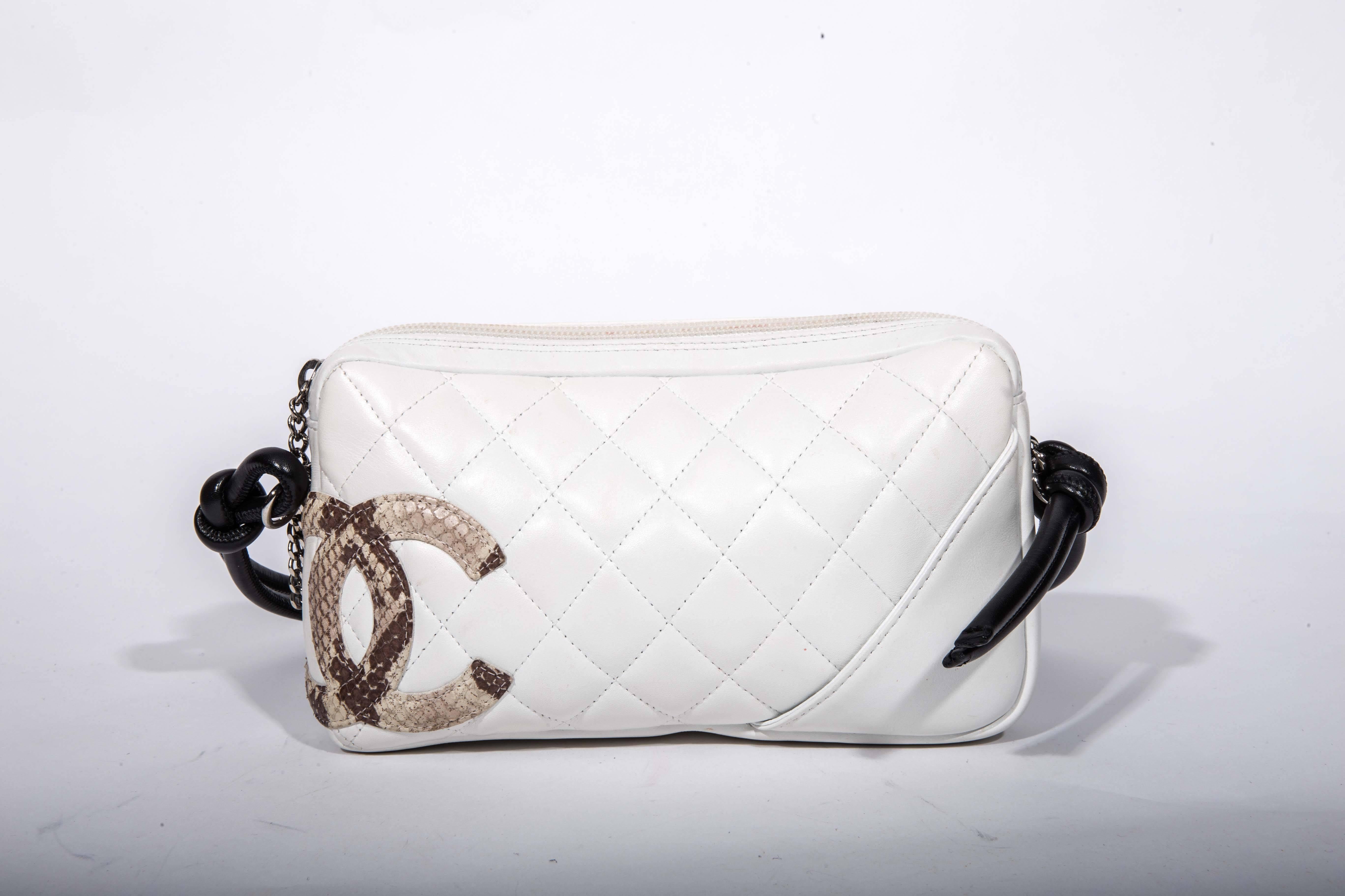 Beautiful pre-owned chic and stylish bag from the Chanel Ligne Cambon collection. 100% authentic. The gorgeous white quilted leather bag features a stylish beige snakeskin CC logo, black leather double strap and silvertone hardware that includes a