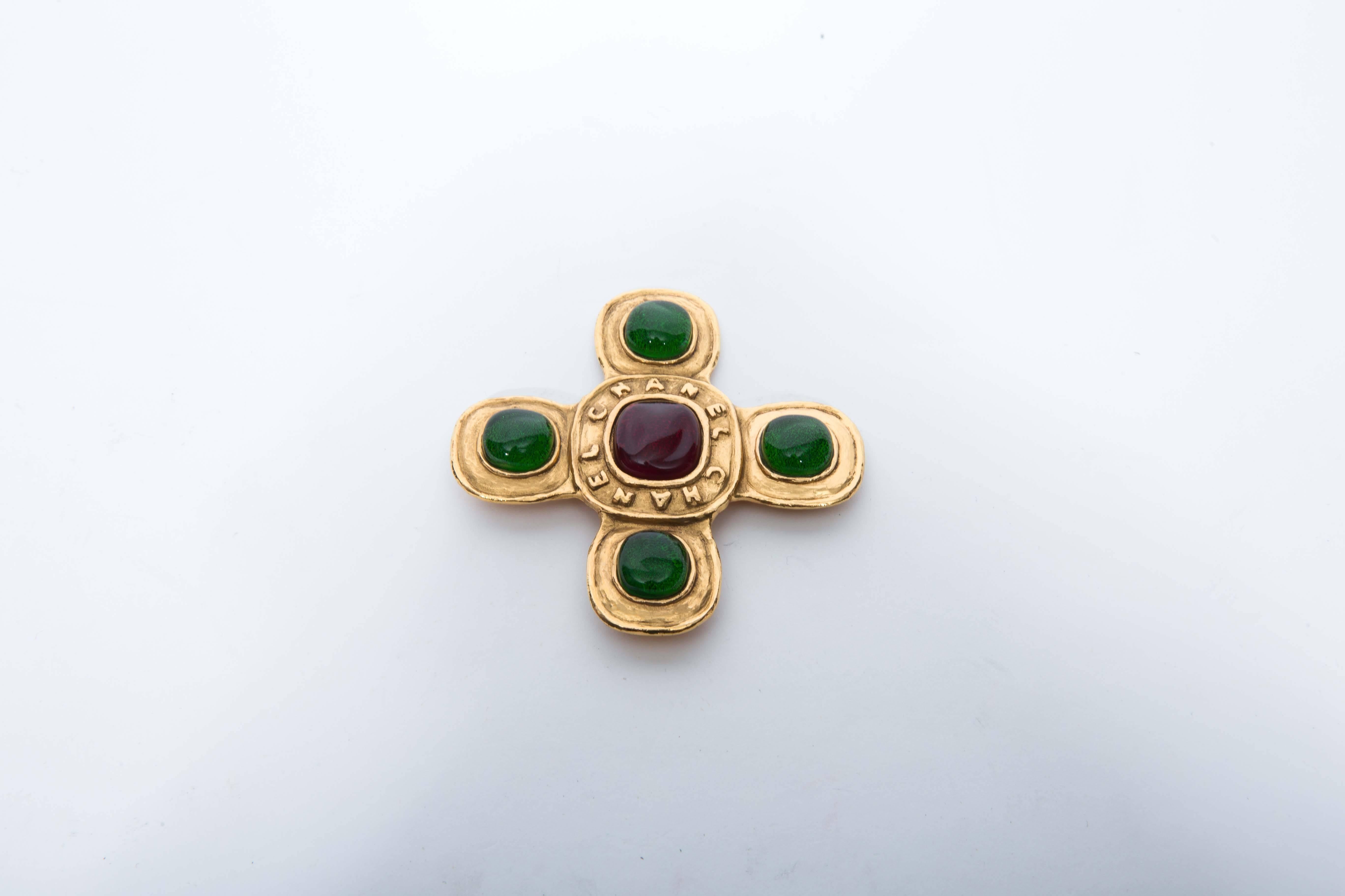 Stunning Chanel Brooch with Five Large Gripoix Stones in Emerald Green and Claret. Embossed CHANEL surrounds the Center Glass Stone. This Piece is in Perfect Condition.