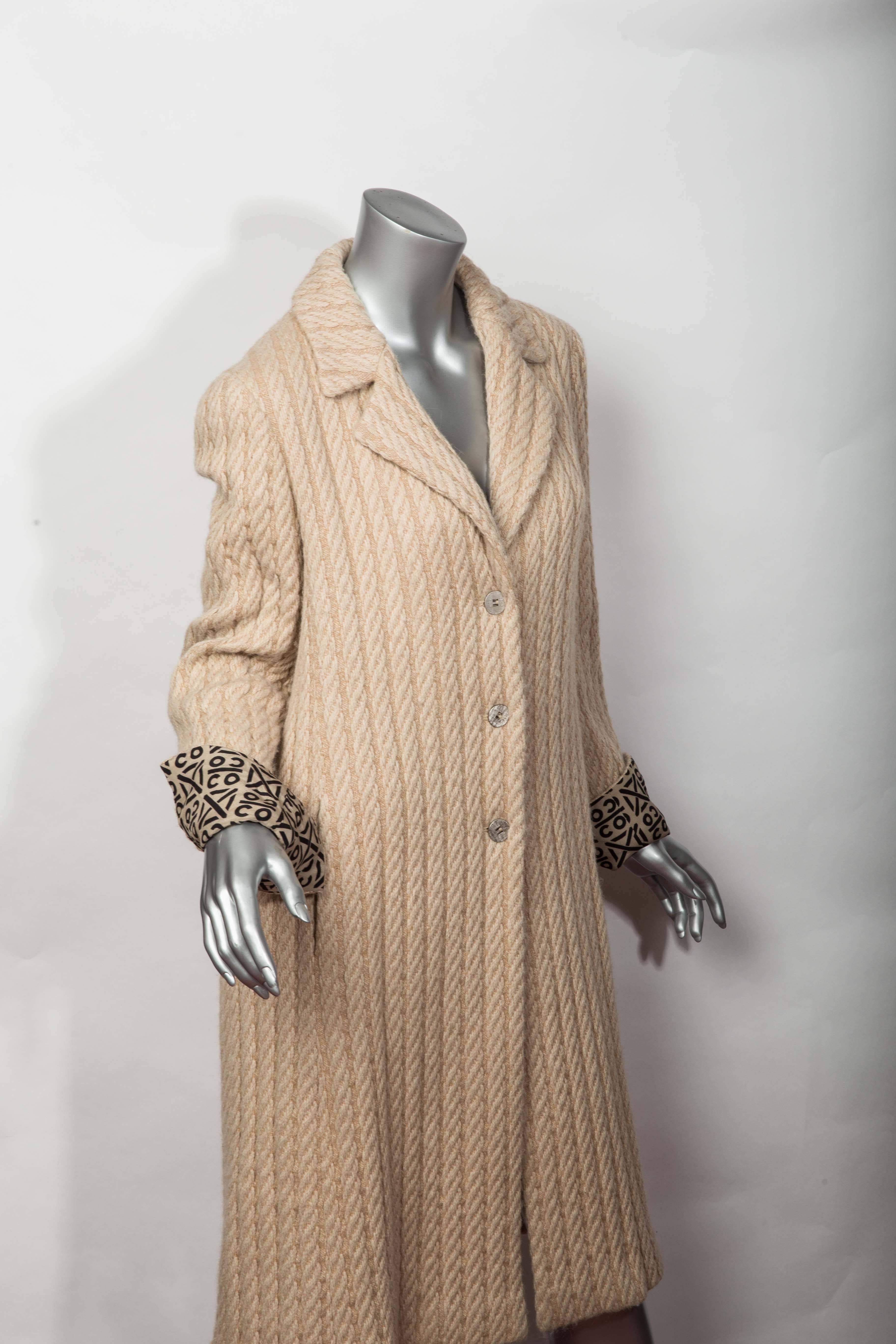 Cream Chanel Cable Alpaca / Wool Coat with Iconic COCO Black and Brown Silk Lining.
Cuffs Fold Over to Reveal Lining.
Notch Lapel with 3 Buttons Down the Front. 
Size 38. Excellent Condition.