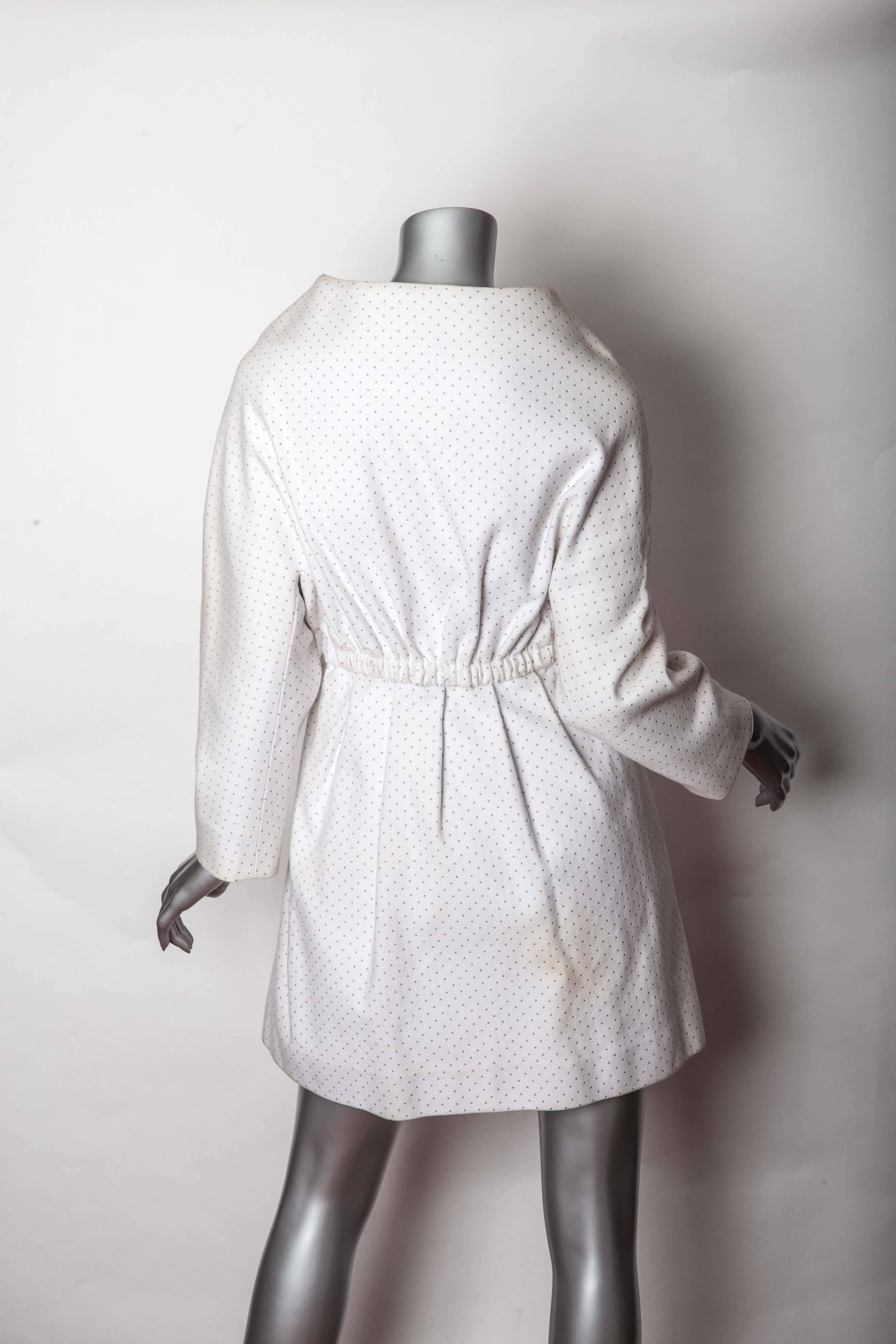 Stunning Vintage Nina Ricci White Coat in Needlecord Cotton. This coat is very sculptural and features an elasticized waist and a v neckline. There is an interior waist band that closes with a hook and eye that enhances the beautiful lines of this