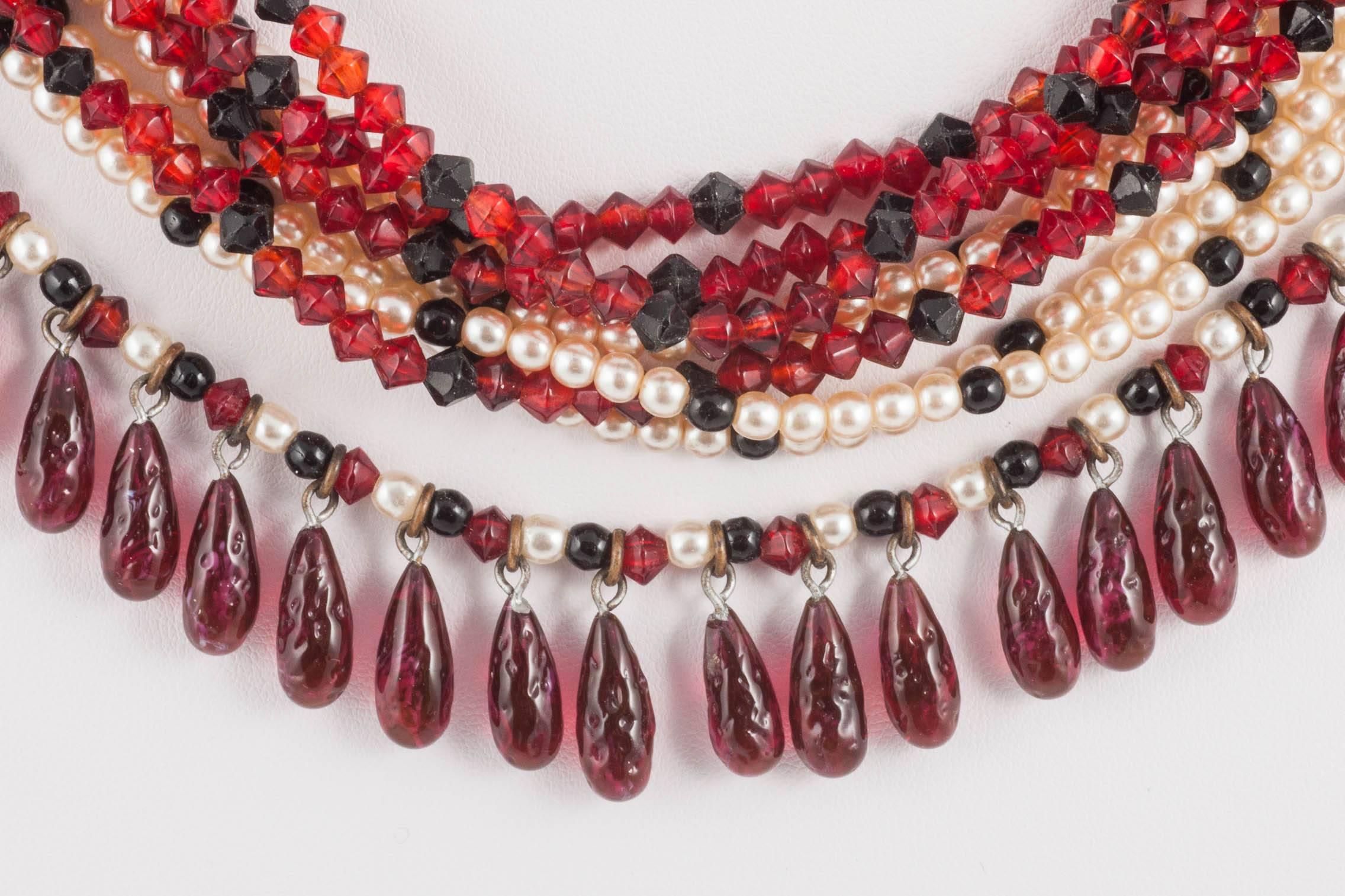 A sophisitcated multi row necklace made by Gripoix , attributed to Chanel, made from small ruby and black glass beads, small pearls, and fringed with tear shaped poured glass drops all round the outer side of the elegant necklace.
This necklace is