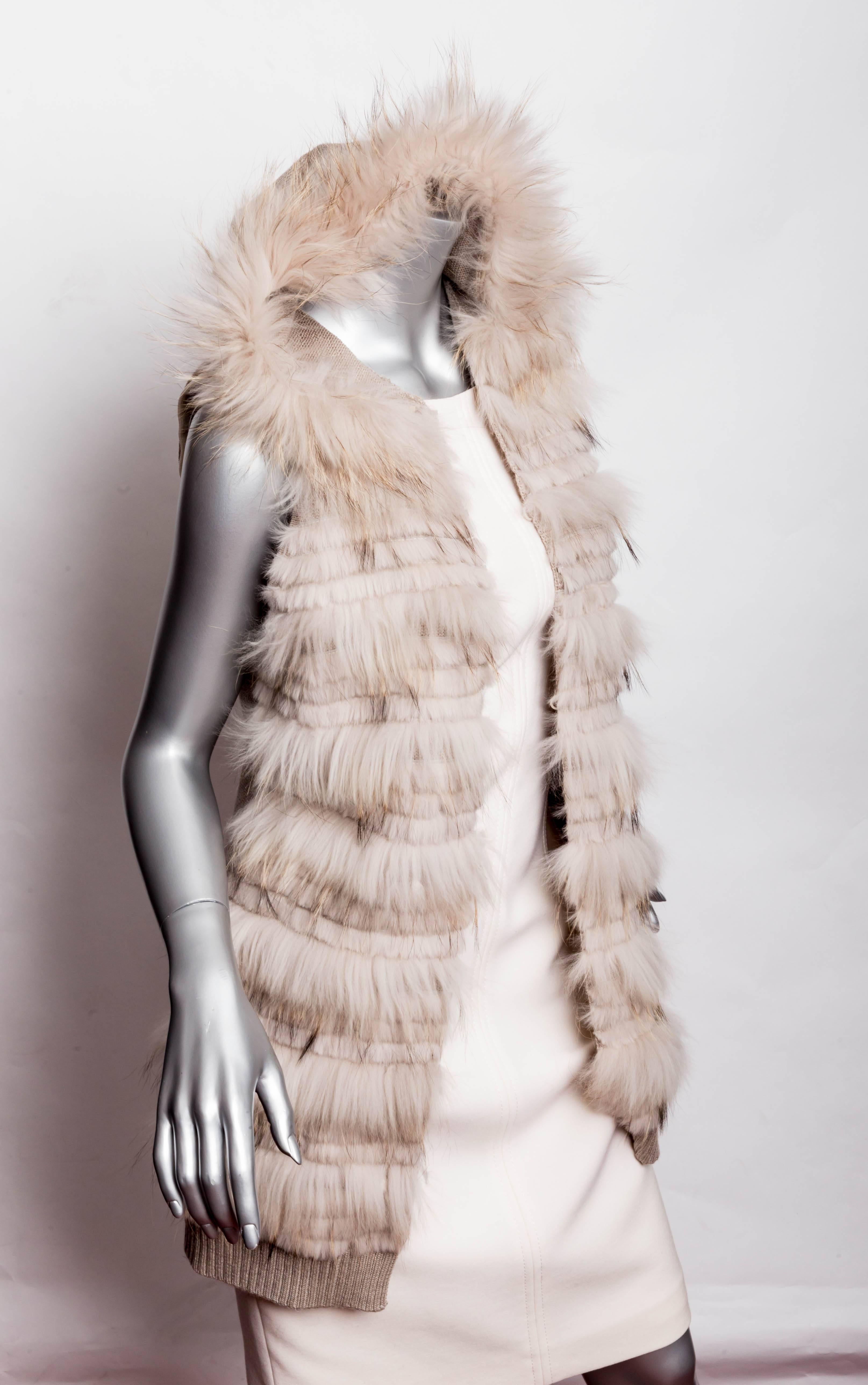 Very cute knit and rabbit fur vest. The front of the vest features horizontal stripes of rabbit fur while the back of the vest is composed of a tan acrylic yarn cable design. This vest reaches the top of the thigh and closes with invisible hook and