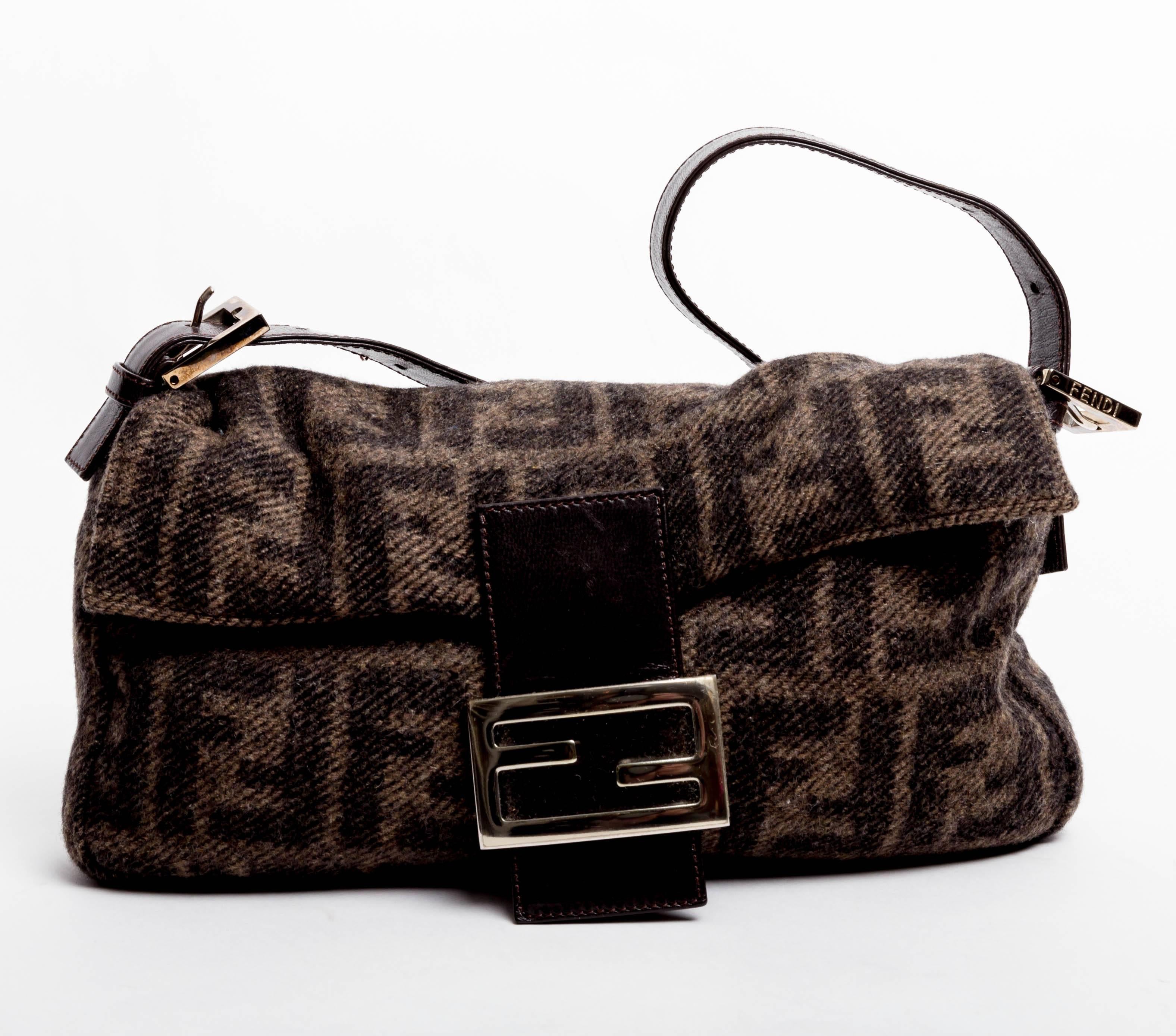 Adorable Fendi Cashmere Baguette featuring the Fendi Logo as the orerall design. With silver hardware and brown leather handle and clasp, this bag is understated elegance at its best. The perfect cocktail party bag. Tuck it under your arm and have