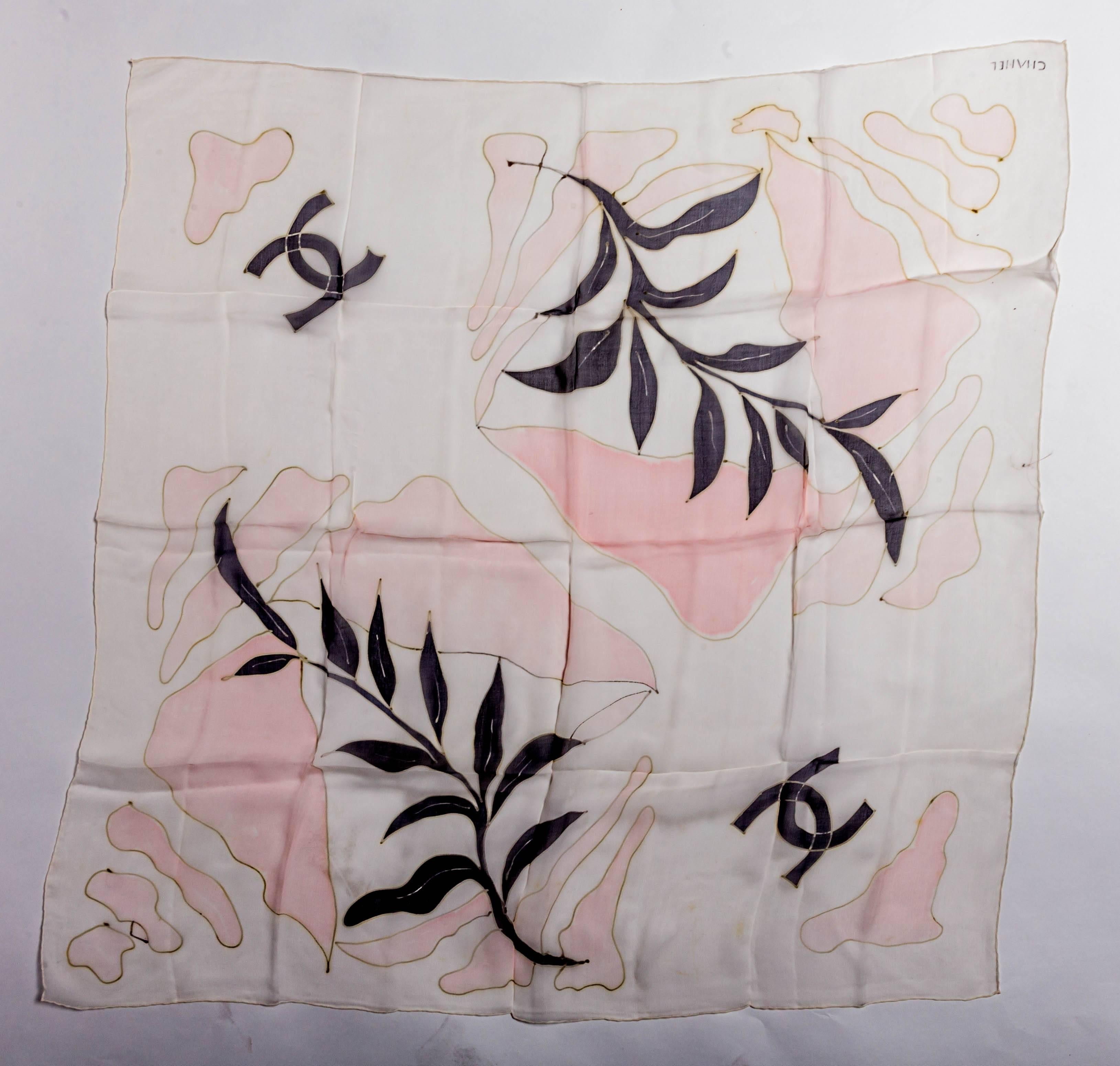 Very pretty and filmy Chanel silk scarf in pink with shades of grey and black. The shape of two leaf fronds decorates this scarf which is also adorned with the Chanel Double C Logo and of course, the scarf is signed Chanel in one corner.
