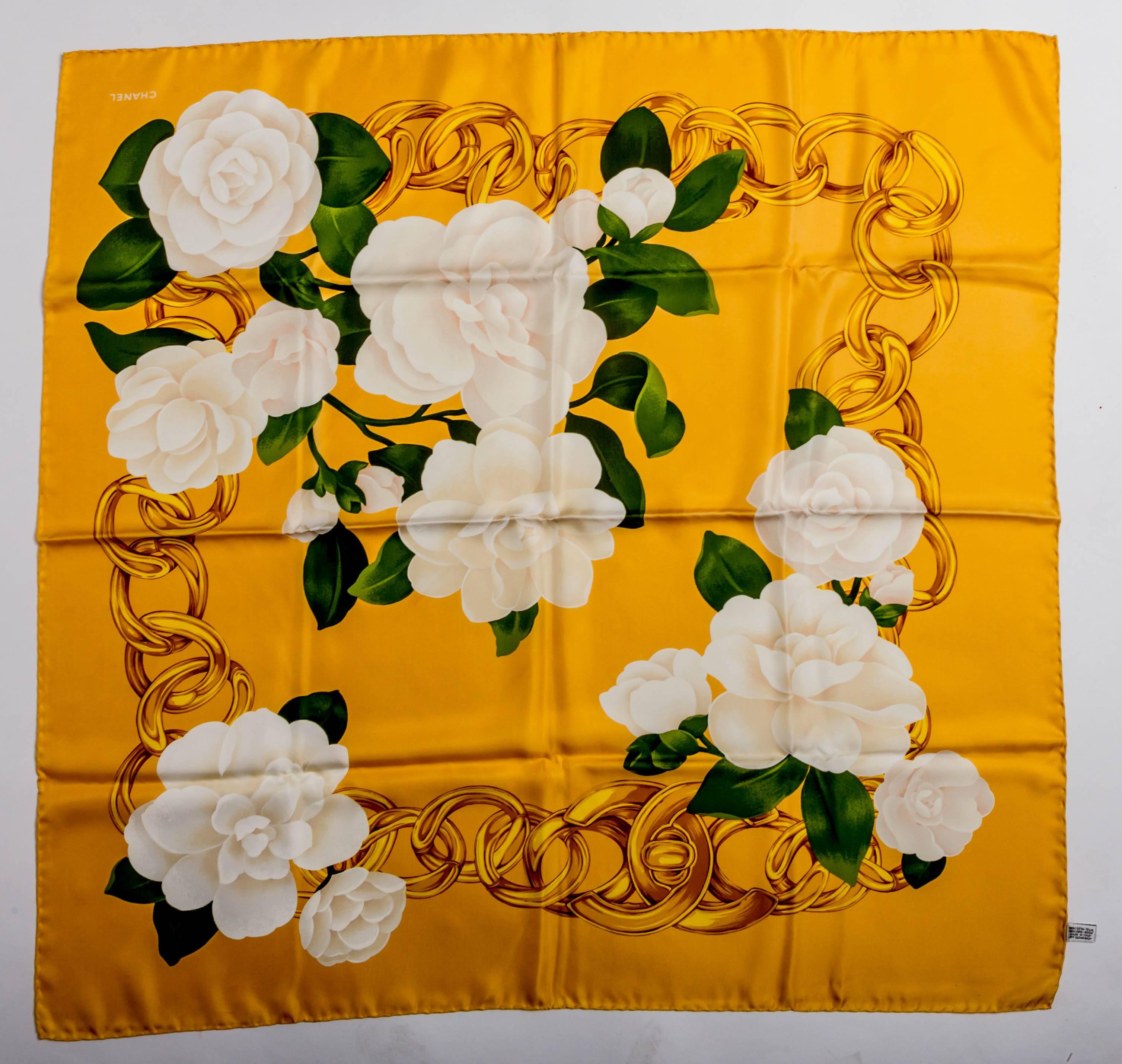 Gorgeous Gold and White Chanel Camellia Silk Scarf.
With hand rolled edges, this scarf is a true work of art.
Green leaves and a gold Chanel chain are intertwined throughout this beautiful piece.
There are a few tiny spots ... too small to