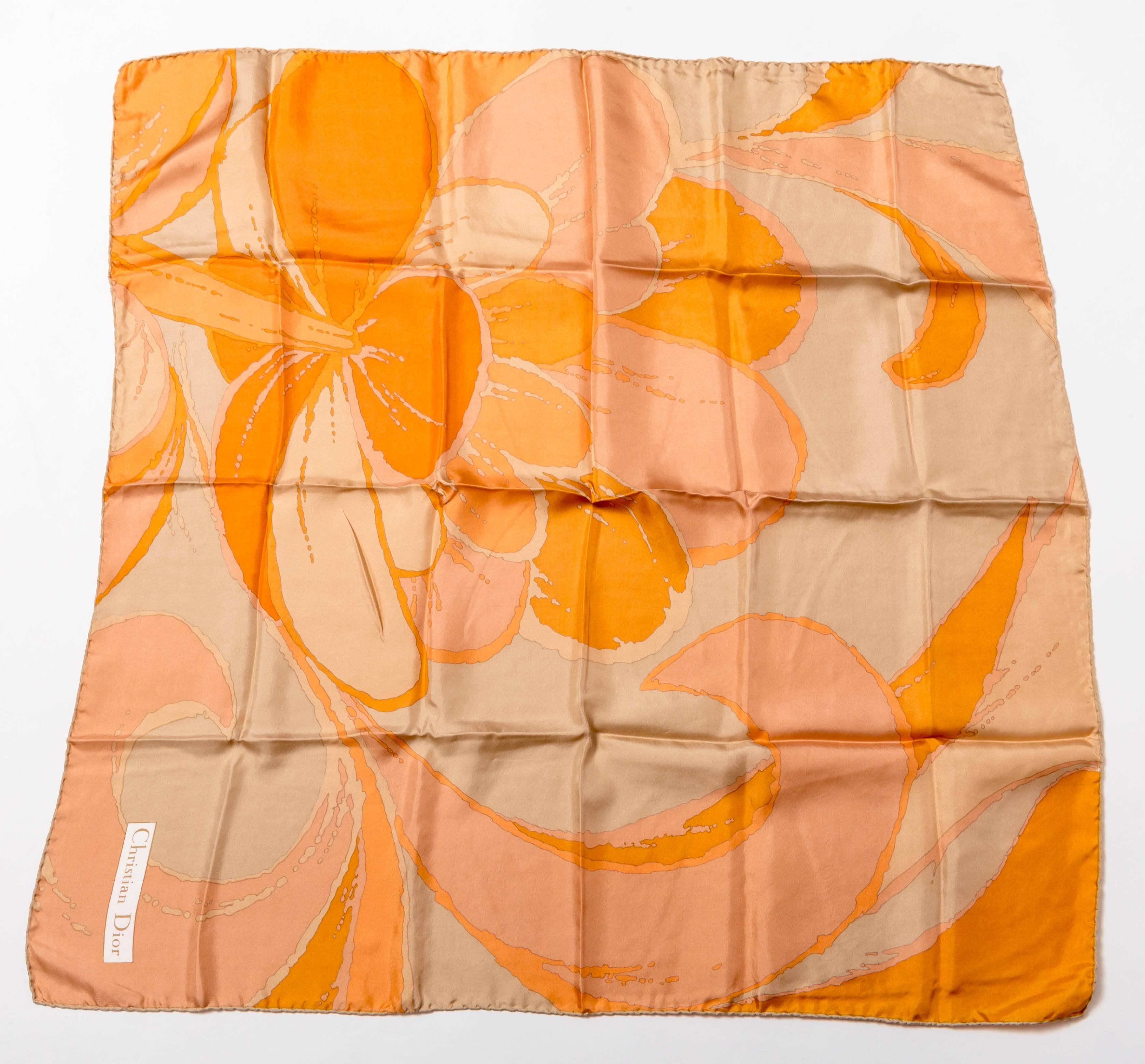 Very pretty Christian Dior scarf in shades of orange. This is a vintage scarf and has a hand rolled edge featuring a floral theme.
