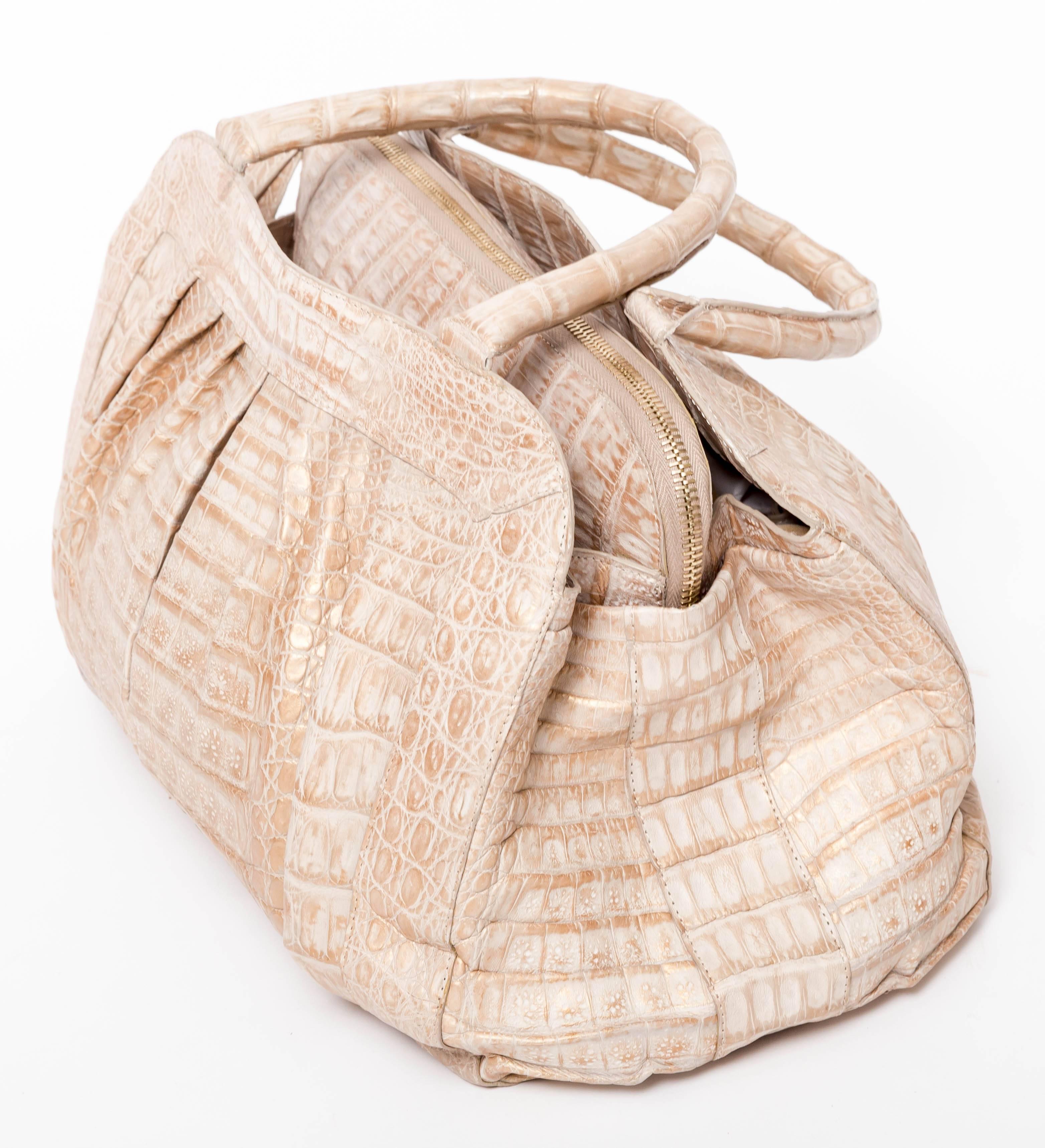 Nancy Gonzalez Structured Cream colored crocodile bag with metallic accents. This bag features two top handles and three center compartments. The central pocket zips closed while the pockets on either side close with a very strong invisible magnet.