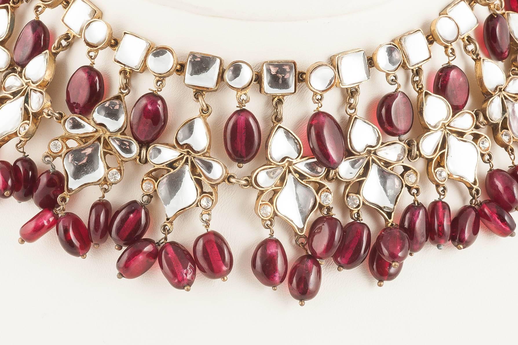 Composed of rich ruby oval glass beads, and clear mirrored glass pieces , this necklace reflects Kenneth Jay Lane's passion for India, and his collections of Indian inspired jewellery. As always with his designs, they are full of a glamour and