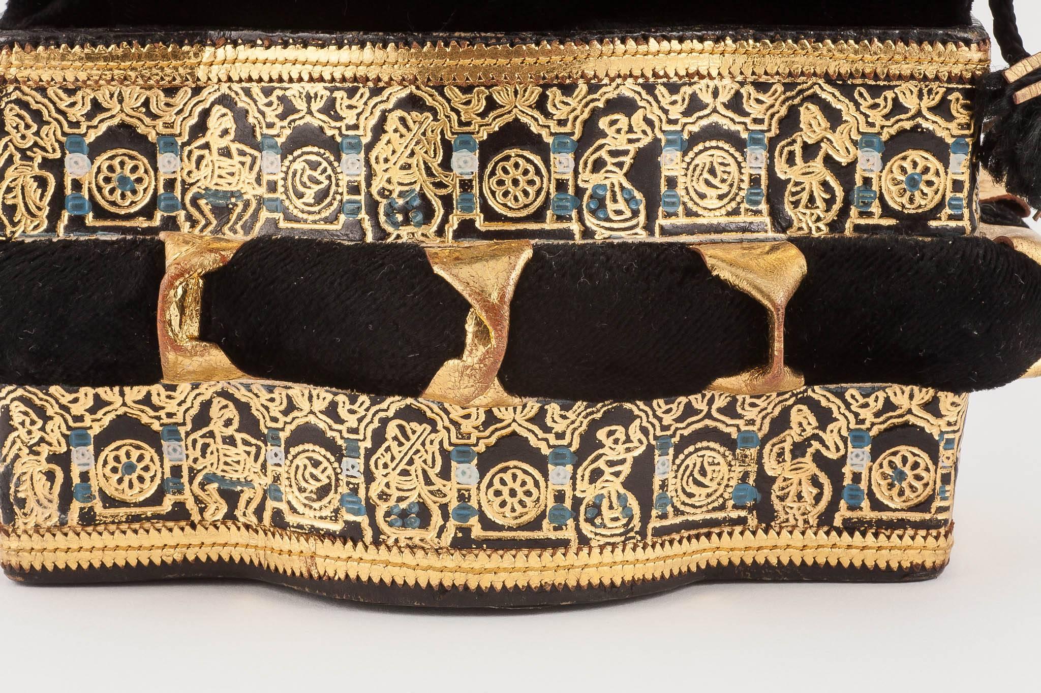 This delightful little evening bag, made of a rigid base of coloured, gilded and stamped leather, with a black velvet drawstring top, channels the eastern exoticism that runs through Hollywood in the early 1940s (films like The Rains Came in 1939