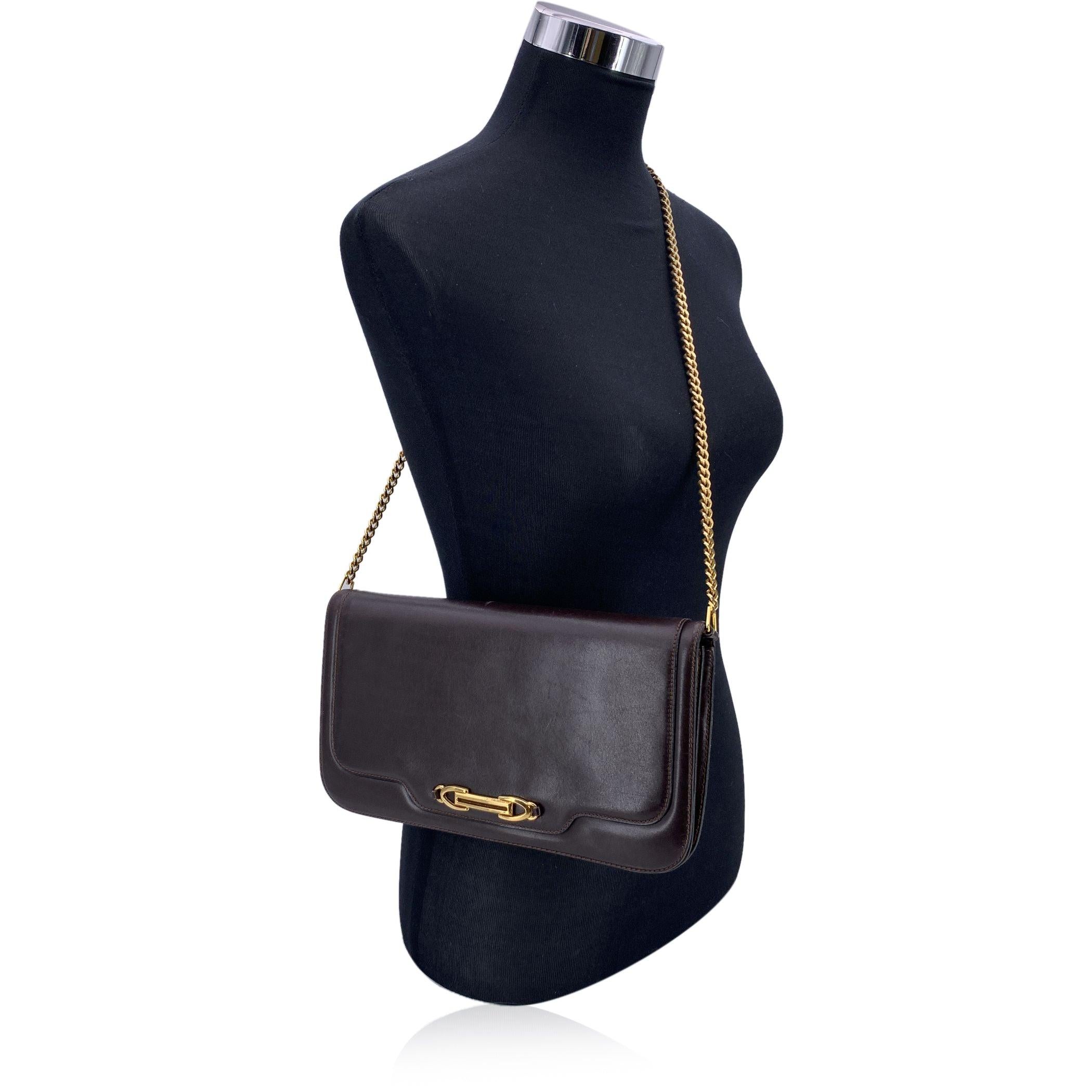 Vintage Gucci Umhängetasche aus braunem Leder mit goldenen Details Diese Vintage Gucci Umhängetasche ist aus braunem Leder gefertigt und strahlt klassische Eleganz aus. Das schlanke Überschlagdesign mit Knopfverschluss und goldfarbenen Metalldetails