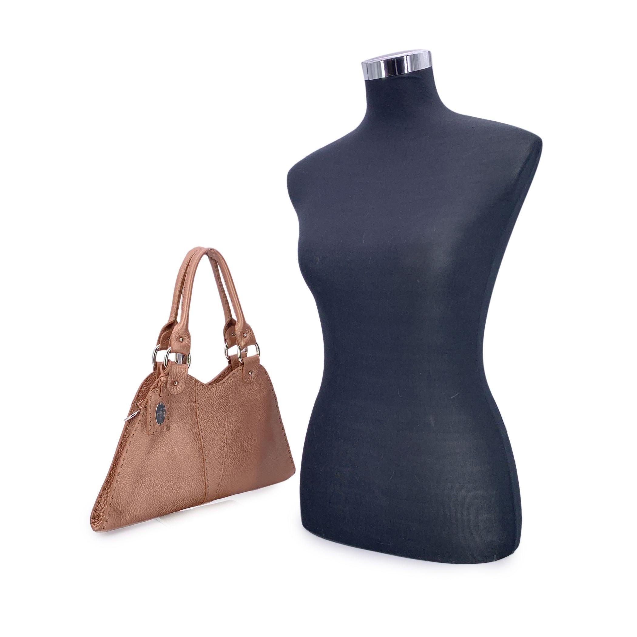 Squisitamente realizzata a mano dai maestri sellai di Fendi, questa splendida borsa hobo Fendi Selleria Devil Trapezio è una vera e propria testimonianza dell'eccellenza artigianale italiana. Realizzata in morbida pelle rosa Cuoio Romano, la sua