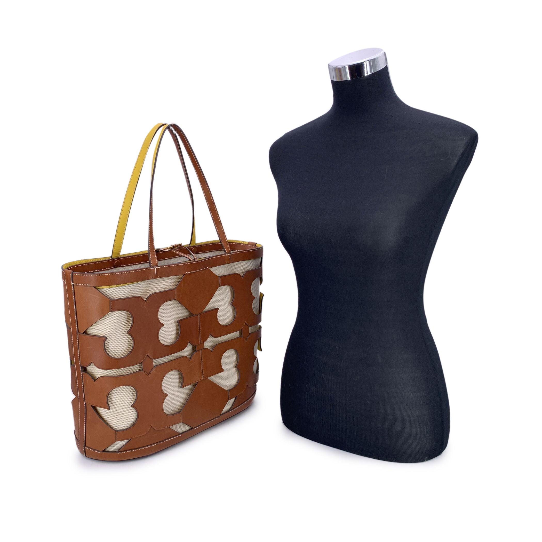 Audacieux et sophistiqué sans effort, ce grand sac fourre-tout Tory Burch à logo découpé est une pièce remarquable fabriquée en cuir marron riche. Le design présente des logos Double T surdimensionnés, découpés au laser, créant un look graphique