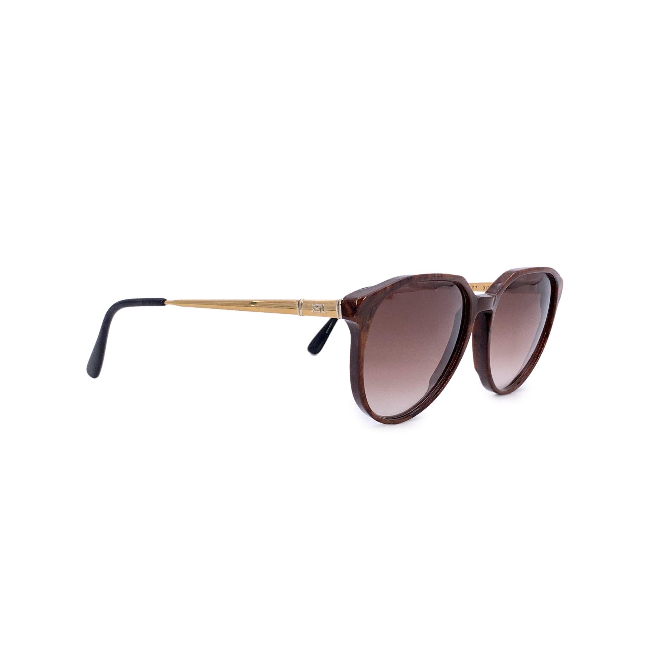 De la época dorada de la alta costura de los 80 nos llega una pieza tan enigmática como su nombre: estas gafas de sol Yves Saint Laurent Vintage Marrón Perséfone son una auténtica encarnación de la feminidad audaz y el encanto atemporal. Fabricado