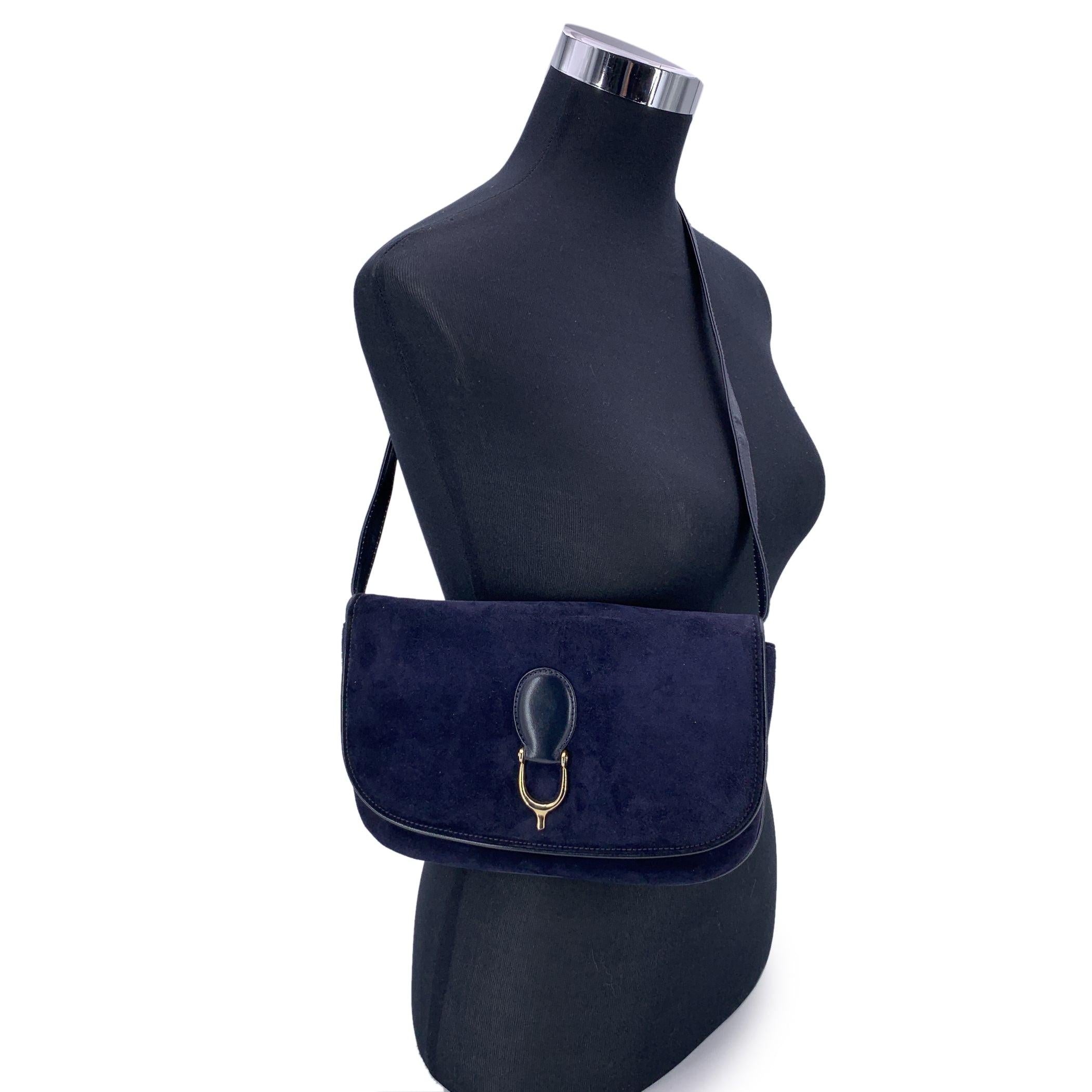 Ce sac à bandoulière vintage Gucci est confectionné en cuir velours bleu marine luxueux, témoignant d'une élégance et d'une sophistication intemporelles. Le rabat se ferme à l'aide d'un bouton et est orné de détails en métal doré sur le devant, ce