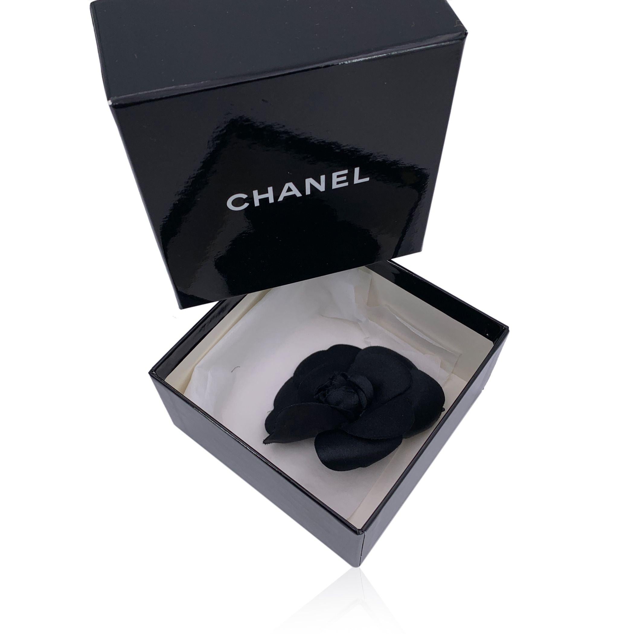 Elegante et résolument classique, cette broche Camélia vintage de Chanel capture l'essence de la féminité raffinée de la maison. Le camélia, symbole de l'éternelle muse de Chanel, s'épanouit ici dans une douce soie noire, ses pétales se superposant