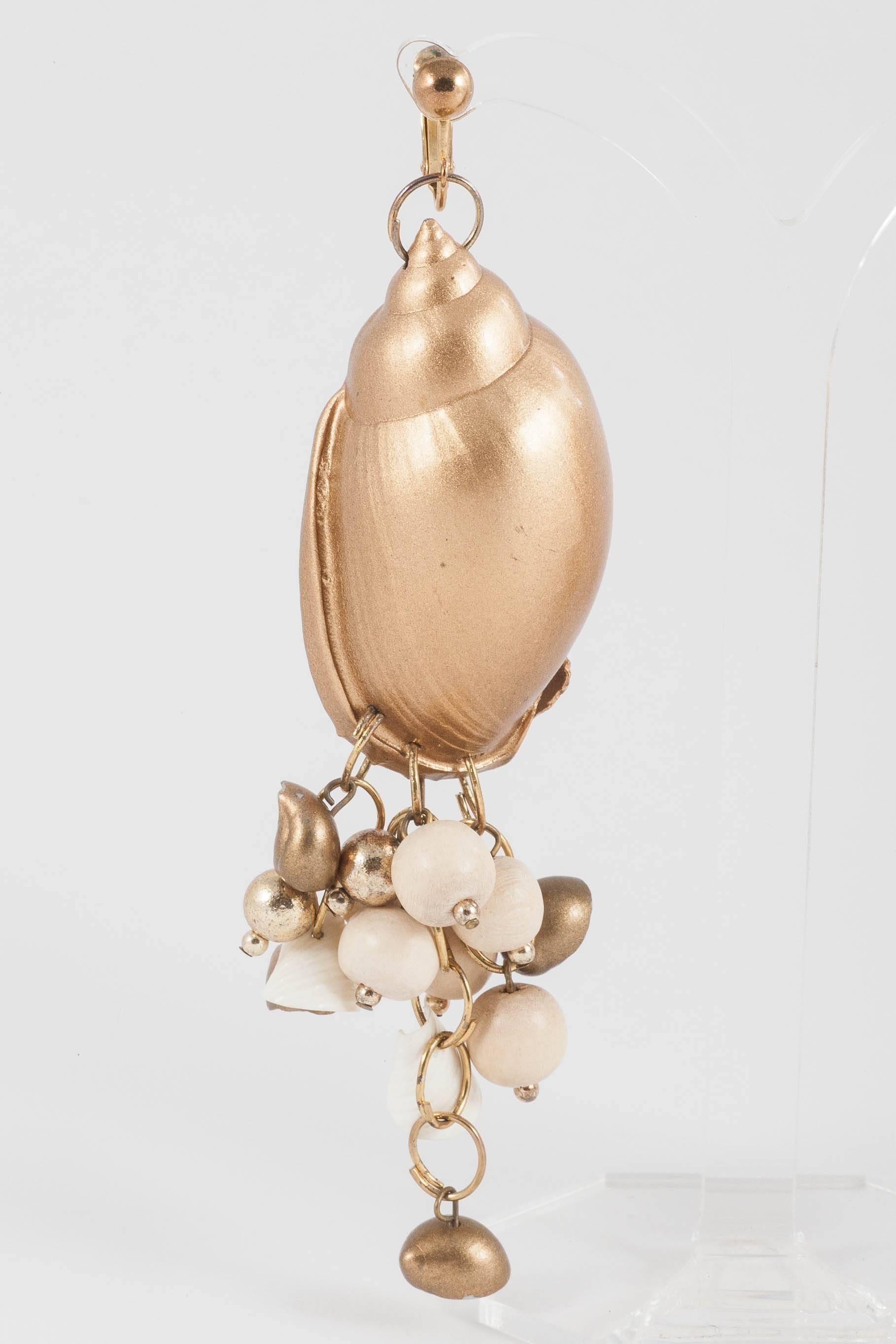 Very long and exotic gilded 'shell' earrings, made from a large gilt shell and cream wooden beads,gilded beads and assorted smaller gilded and plain shells, with adjustable gilt metal clips. Very glamorous and striking,surprisingly light, they have