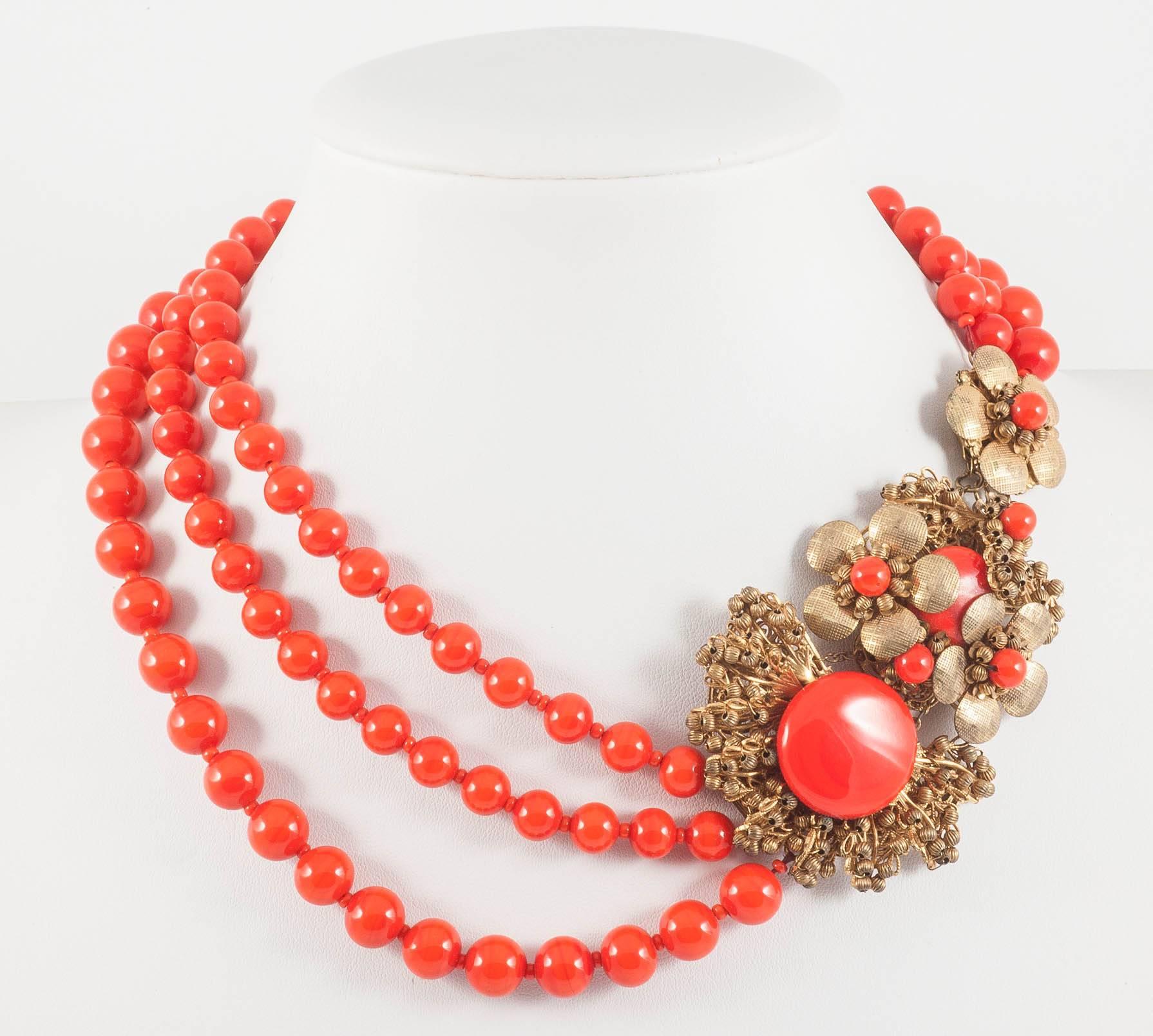 A vibrant and joyful red glass bead and button necklace, with a strikingly ornate clasp/sidepiece, designed by Robert Clark, for Miriam Haskell in the 1960s. The clasp, which is subtlely hidden, is made out of characteristic filigree gilt 'flowers',