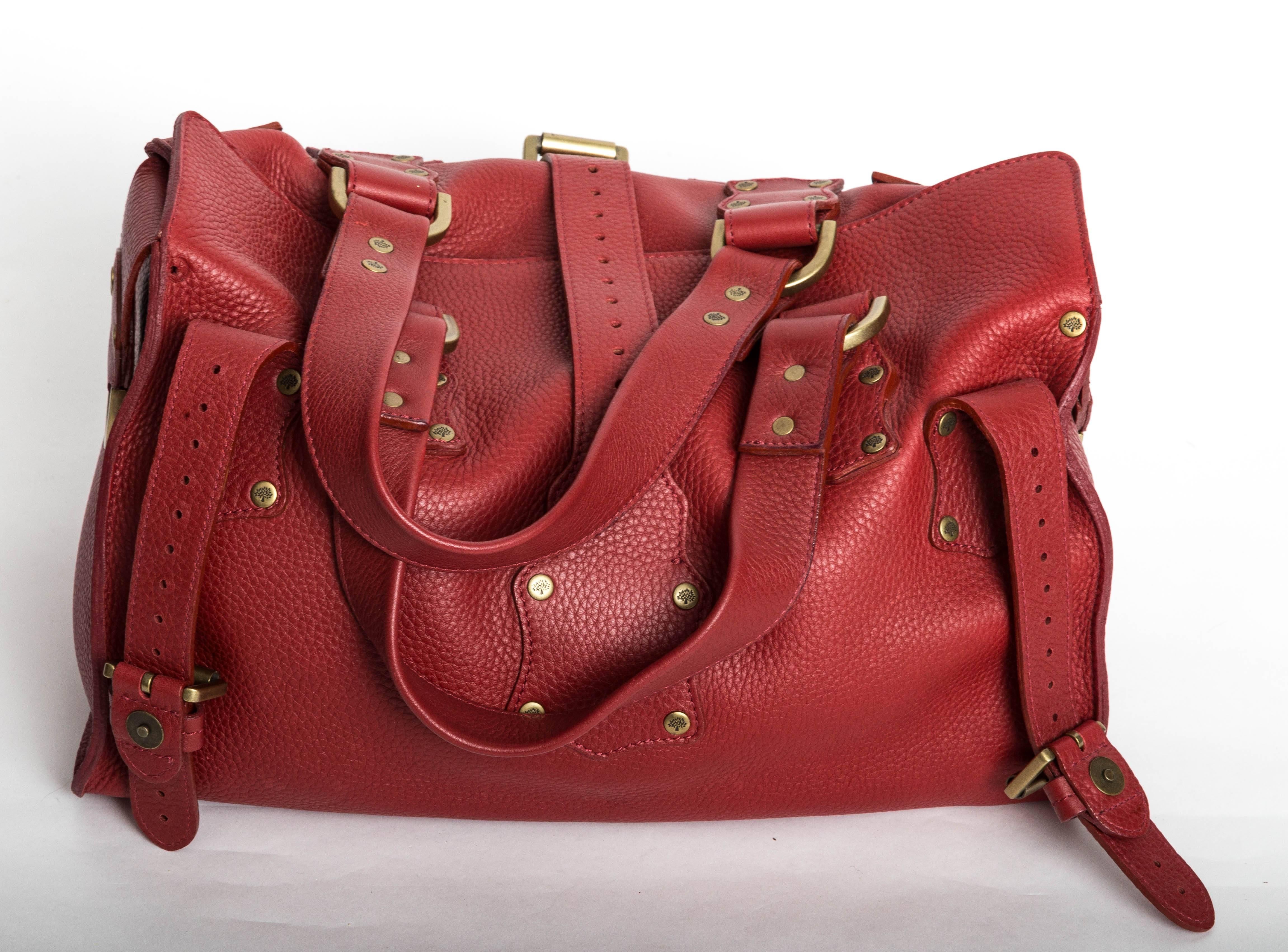 
Red leather Mulberry Roxanne Bag with antique brass-tone hardware, red stitching, dual pockets with snap closure at front exterior, studded accents at exterior, buckle accents at exterior, D-ring accents at side exterior, dual flat shoulder straps,
