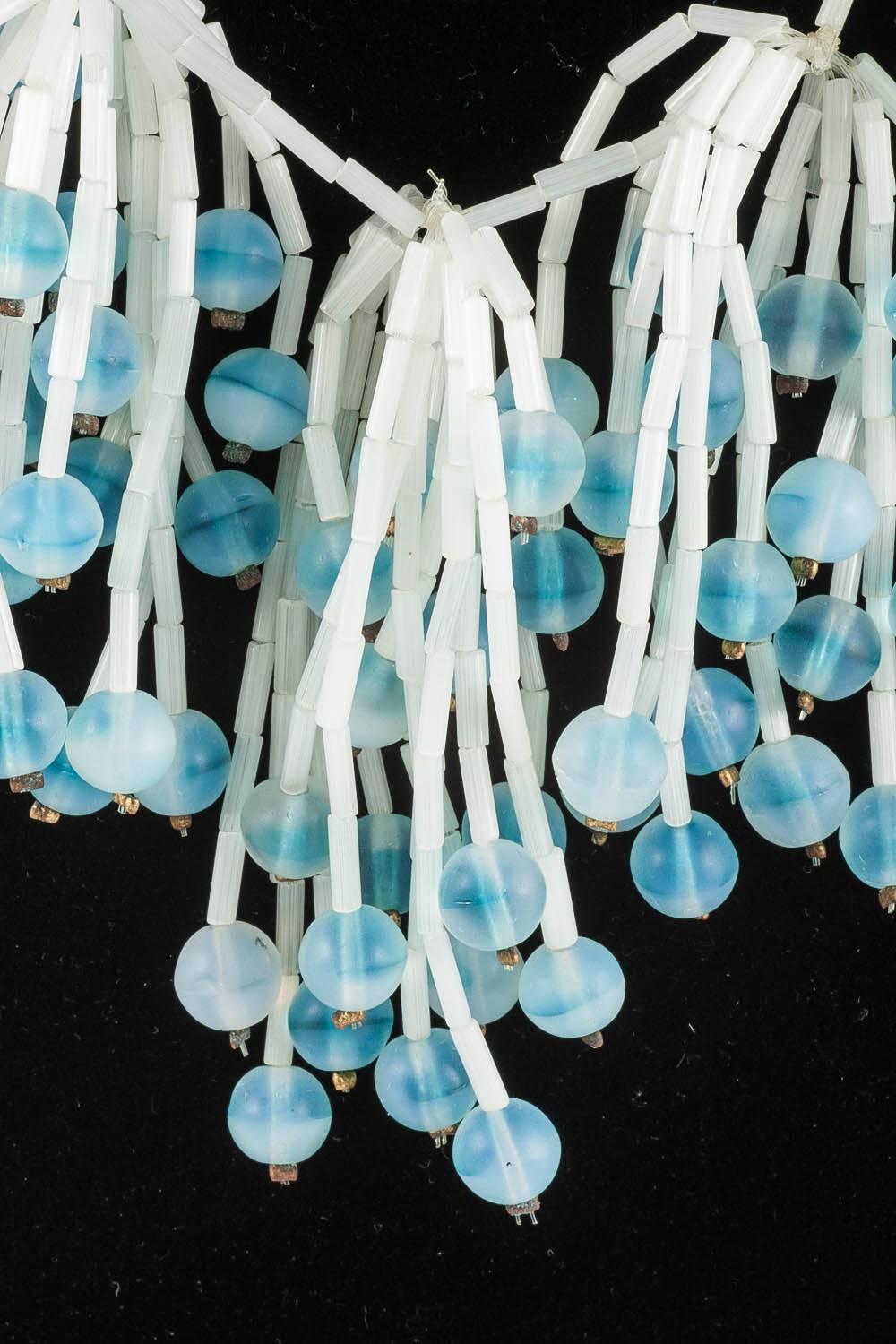 A delicious necklace from Langani, Germany, made from cascading frosted glass tubular beads and frosted round beads with an irregular soft blue tint. The clasp of a large white glass cabuchon is the typical Langani fitting.Similar to their famous