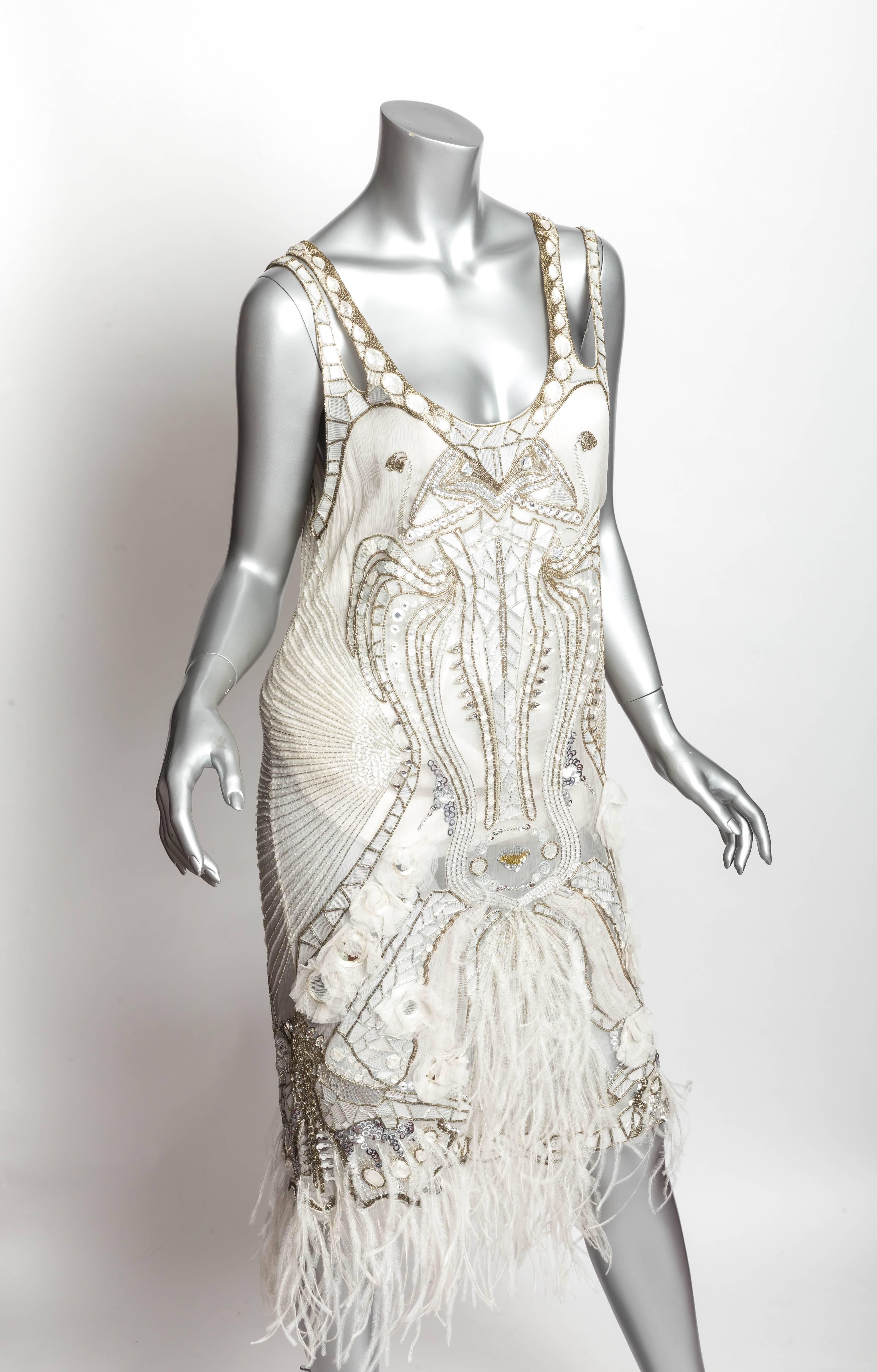Absolutely stunning Emanuel Ungaro Paris cocktail dress in off white with illusion netting trim. Small pieces of mirror outline the lines of this dress which is also embellished with beads, faceted glass  and ostrich feathers. 
Size 44
