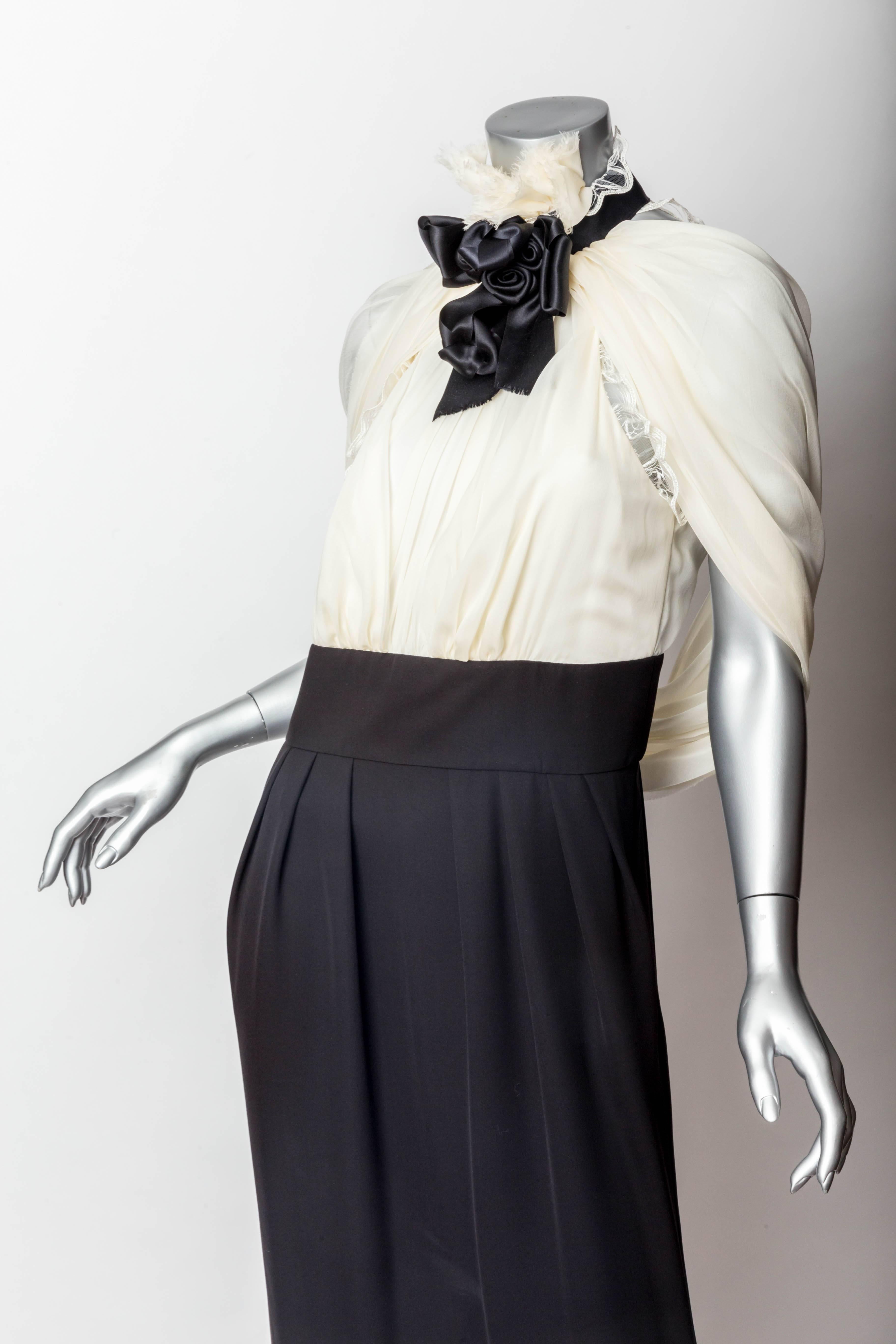 Wonderfully chic Chanel Evening Gown - Size 42
Ivory silk halter style top with sheer silk panels that can be worn to cover the shoulders or draped on the back of the dress.
Lace trim to top. 
Quintessential Chanel black silk bow detail to