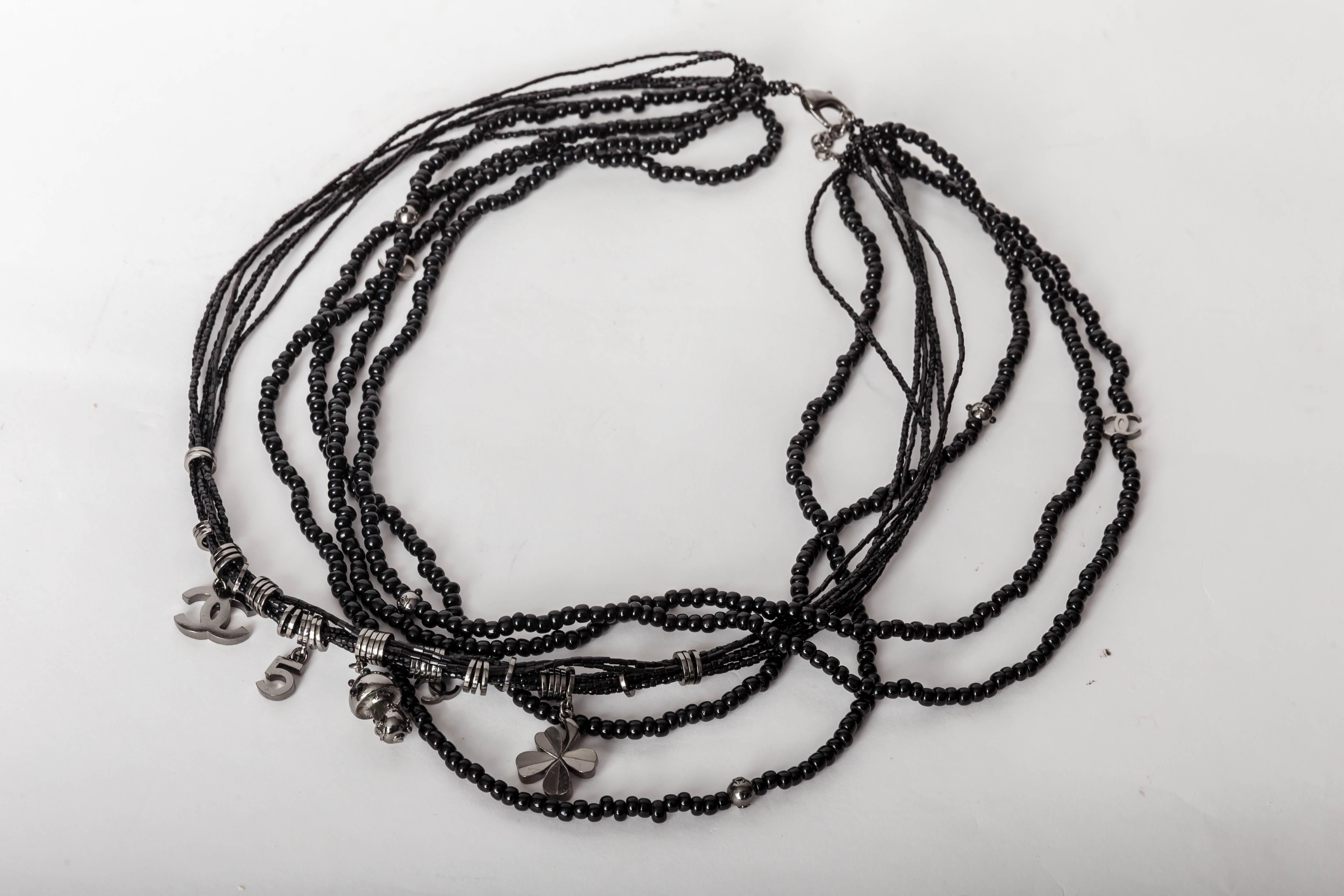 Rare Signed Chanel Multi Strand Black Beaded and Crystal Necklace Interspersed with Silver Beads and Chanel's Iconic Charms Including a Four Leaf Clover, Interlocking Chanel CCs and the Number 5.
Condition is Excellent with the Exception of a