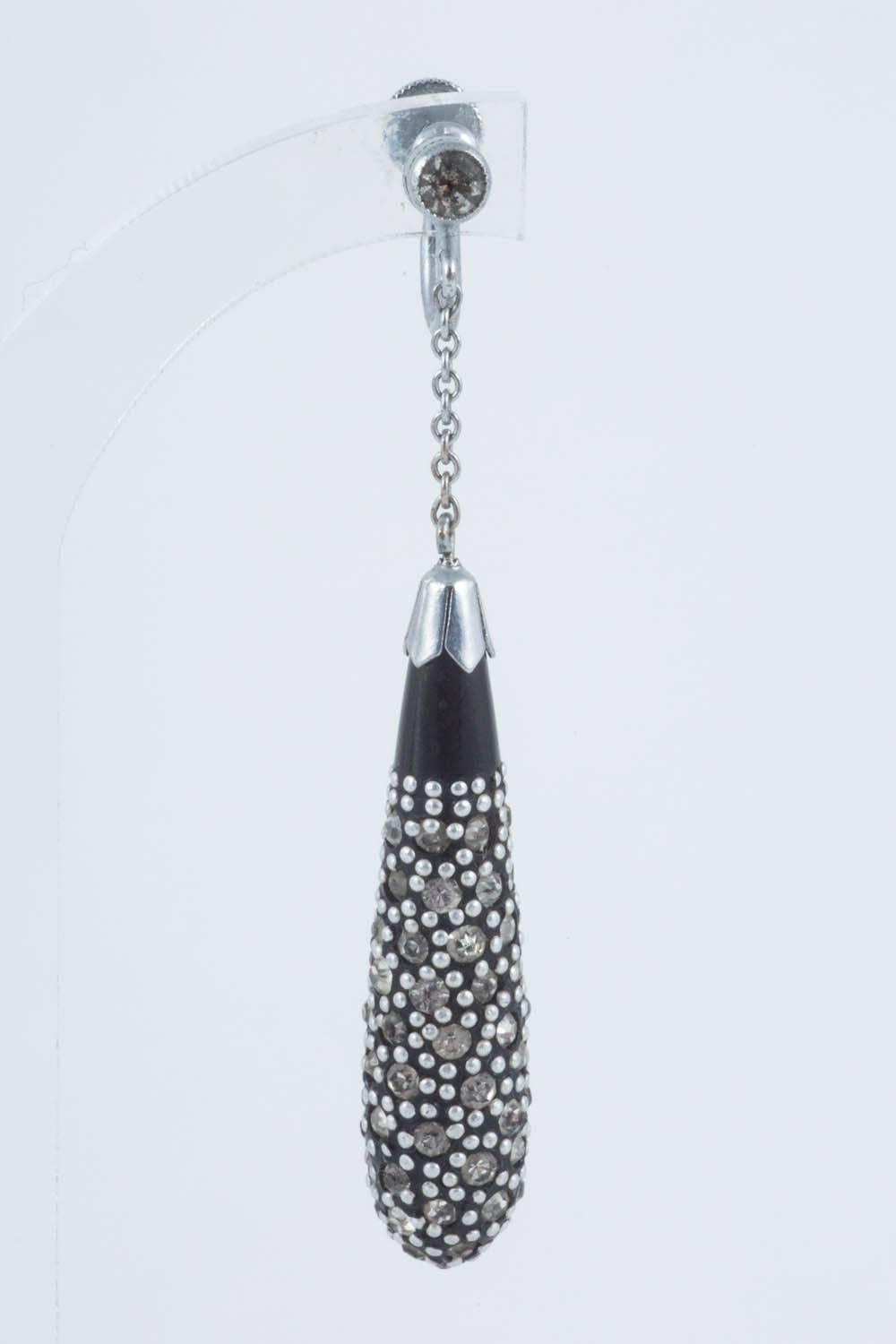 The elegant pendant earrings, are made from black Bakelite and studded with pastes, as well as small chrome ball/spots. They are set off  with a matching paste that sits on the ear. Made in France in the 1920s, they contain that Art Deco style and