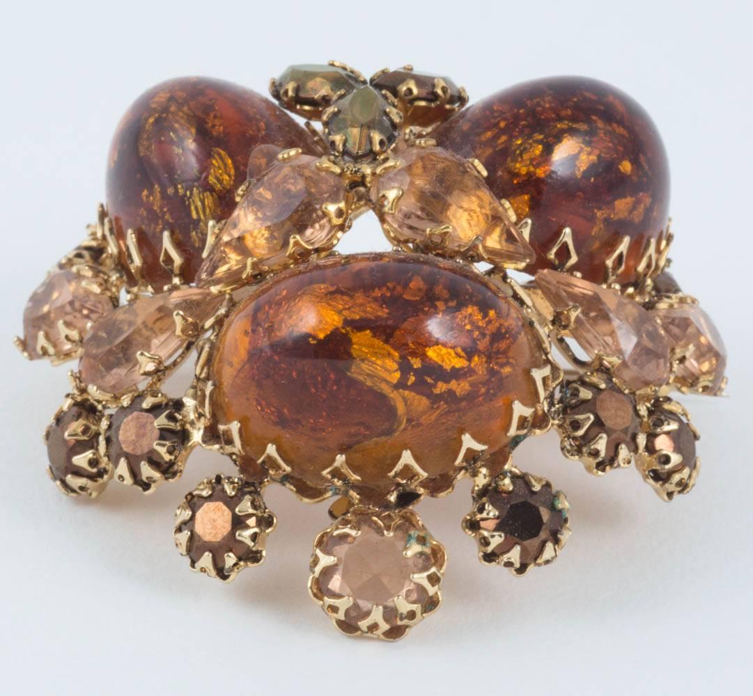 This brooch is extraordinary. The three huge Lucite faux amber cabochons are set in gilt metal in a dome shape with apricot paste in rounds and navette shape glass. Also, in those shapes, are metallic bronze set paste. The sum total of all these
