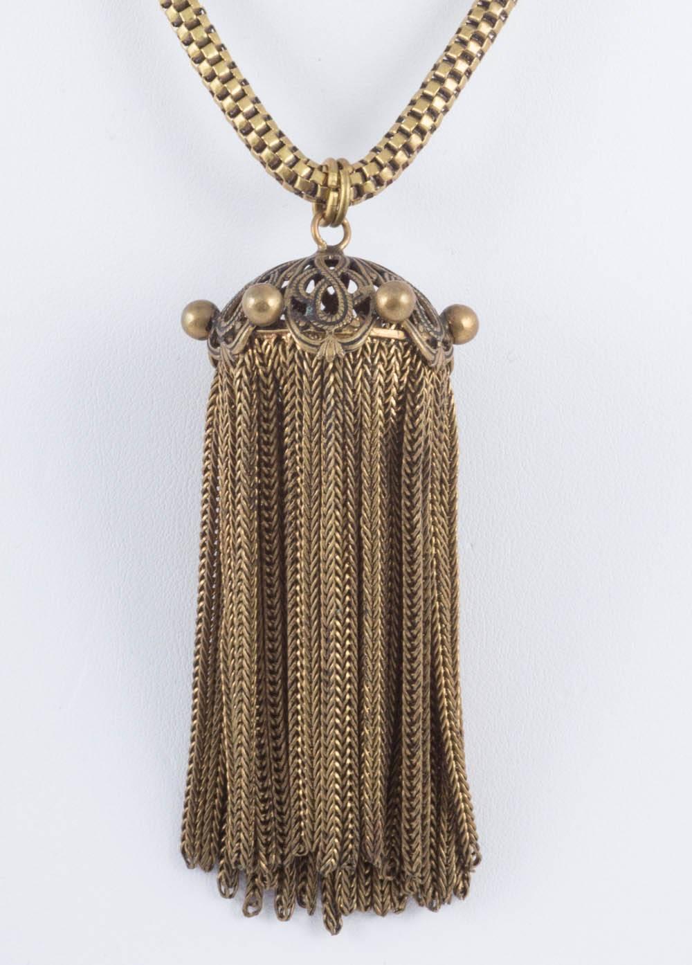 This is an extravagant brass tassle pendant on a collar bone length chain of the same period. They came together, but the pendant would look equally good on a long chain also. The pendant is well made with slinky snake chain ropes making up the