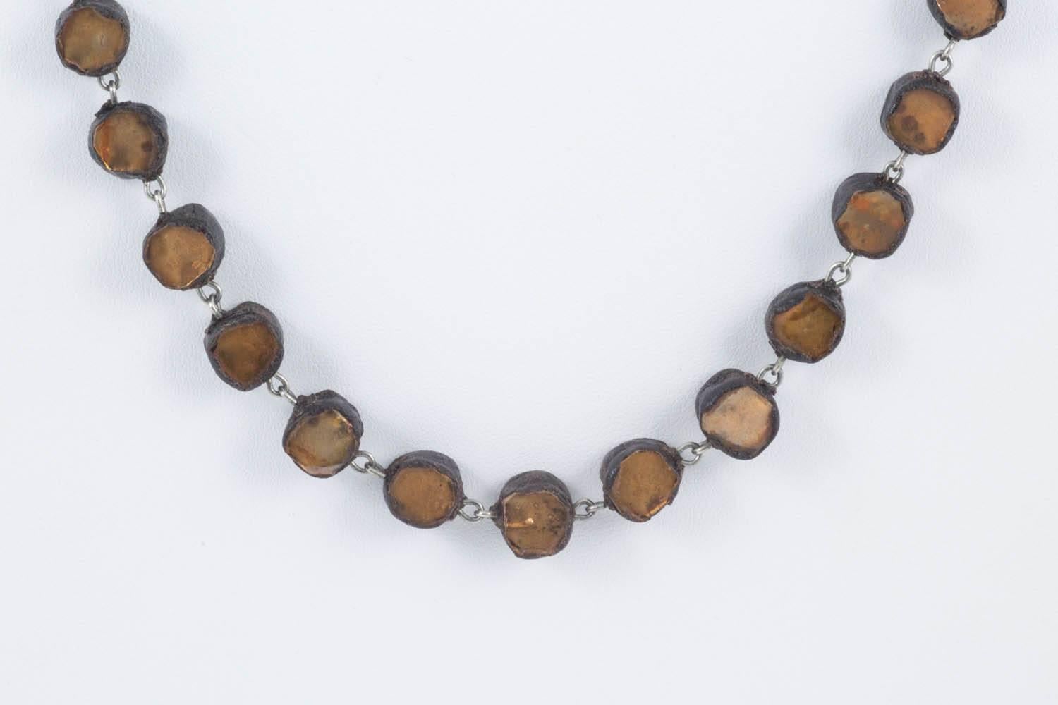 A magical single row necklace from Line Vautrin, magician and poetess of jewellery, created in the 1960s. Made from 'talousel'  (a type of resin popular in the 1960s) and fragments of golden bronze mirror, it is a classic and simple piece, an easy