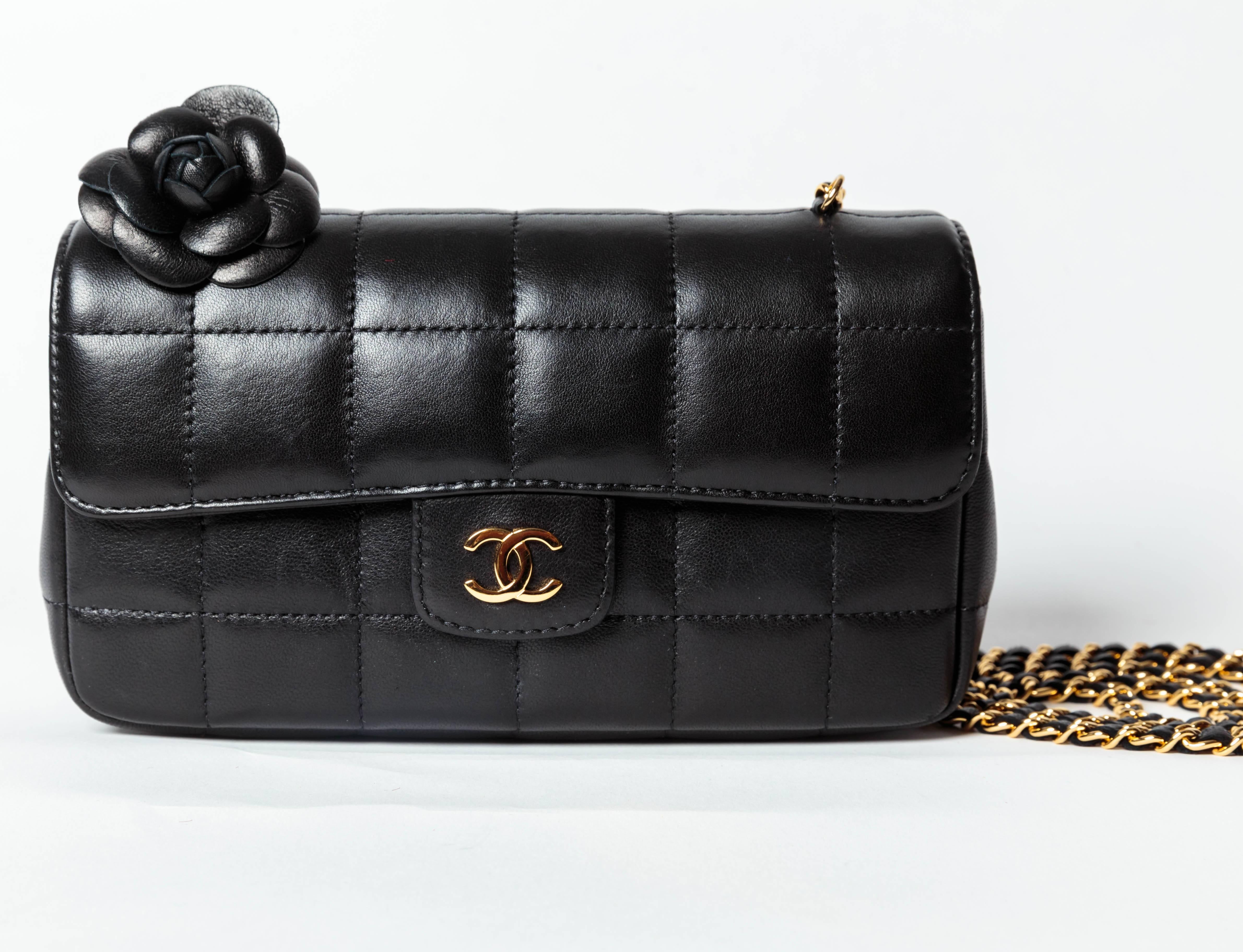 Stunning small Chanel shoulder bag in quilted black lambskin with gold chain strap. The bag features a layered leather camellia.
Chanel logo fabric lining with one flap pocket. 
Condition is excellent. Original Chanel box and dustbag are